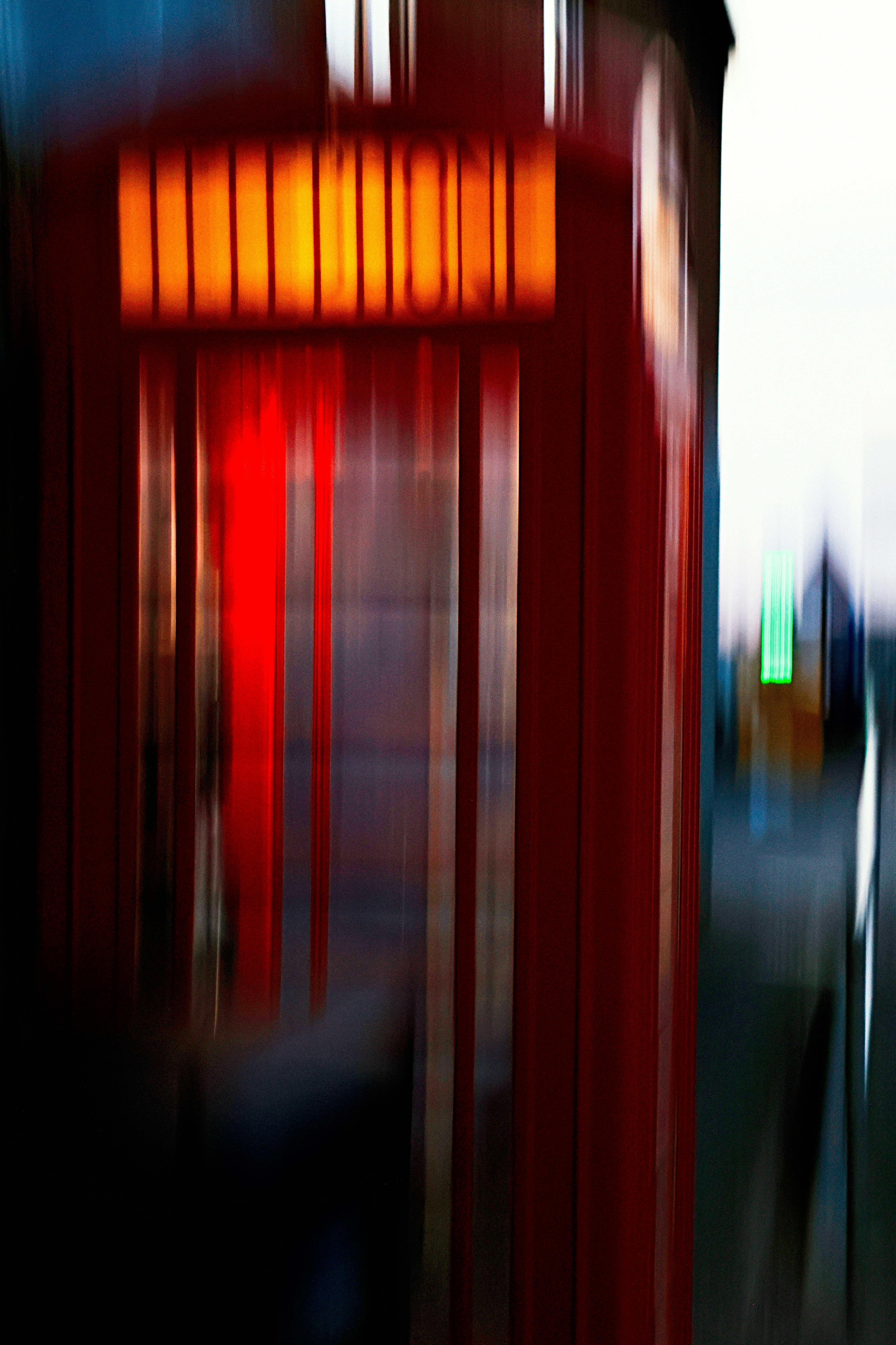 Una cabina telefonica rossa sfocata dal movimento con un'insegna luminosa su una strada della città