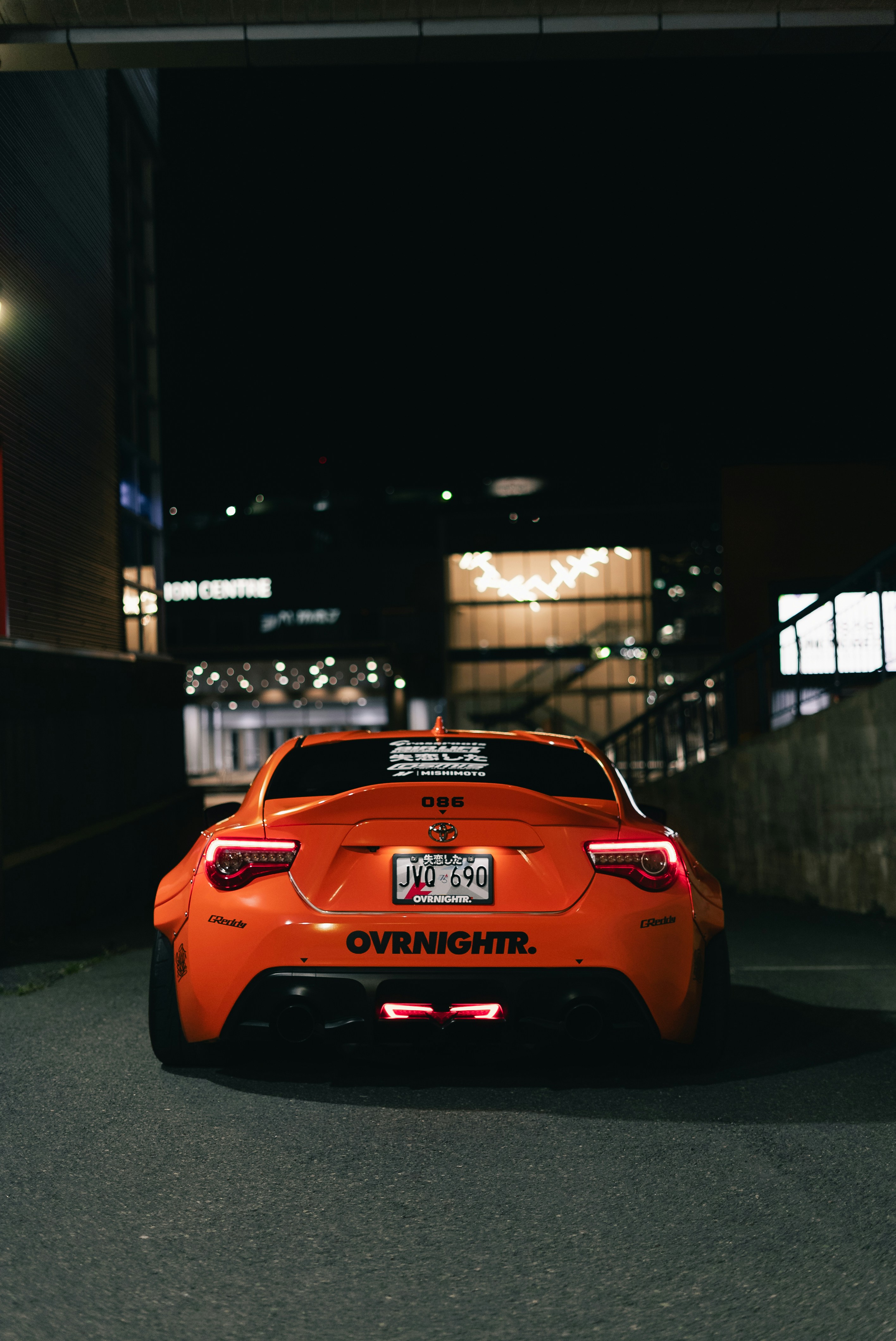 Rear view of an orange Toyota 86 sports car parked at night