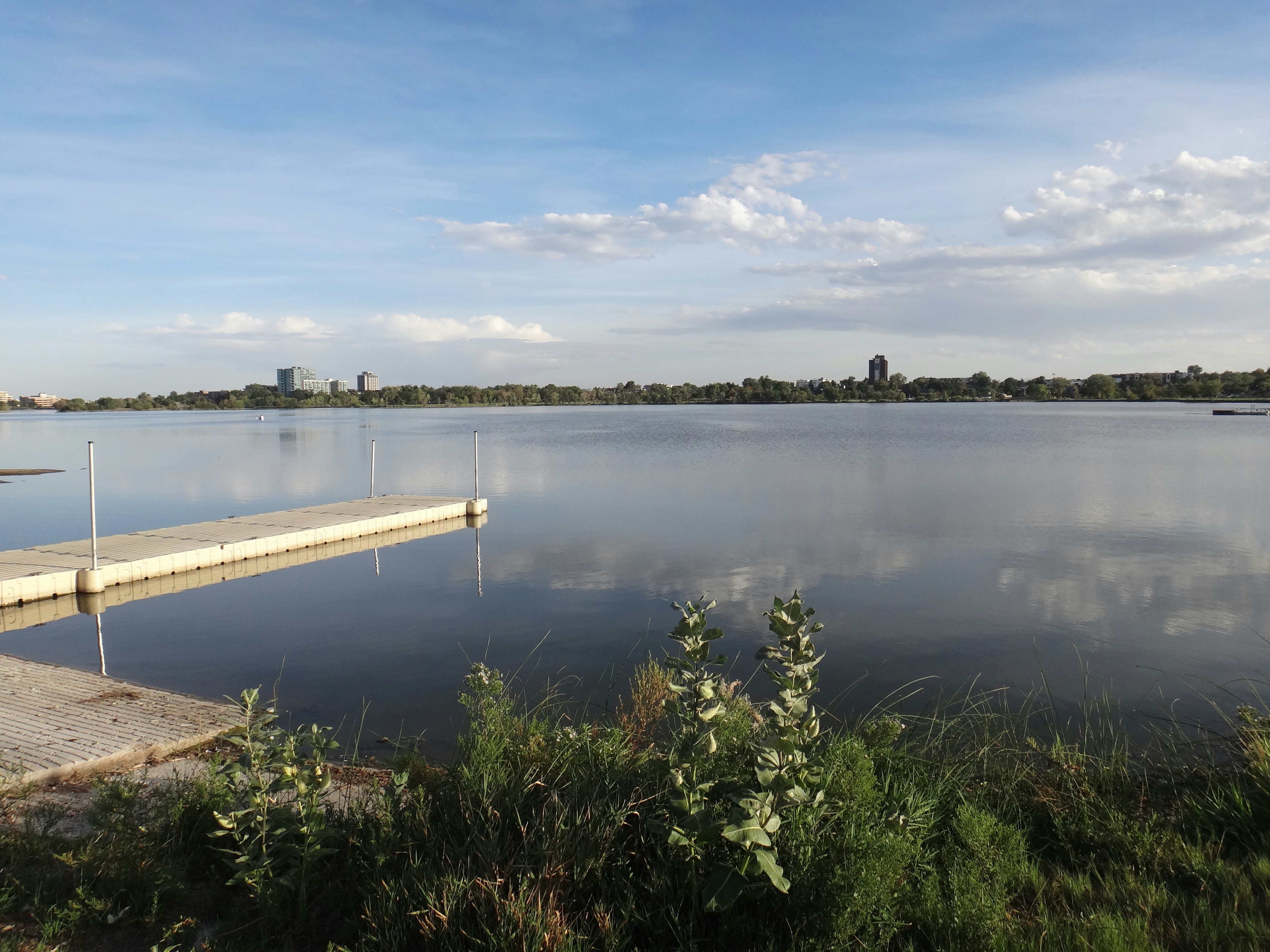 A floating dock on a calm lake with a distant city skyline