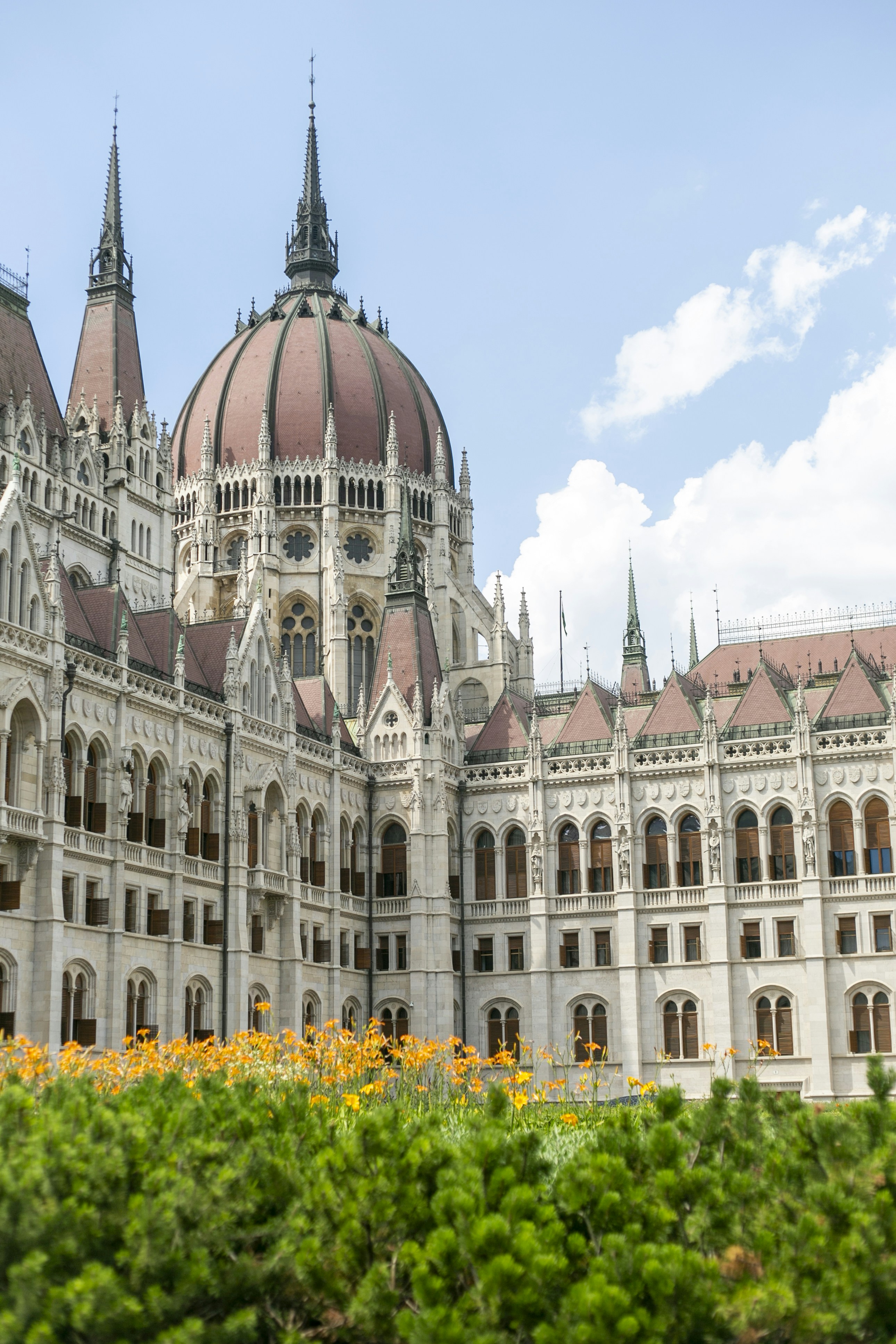 The Hungarian Parliament Building with its central dome behind orange flowers in Budapest