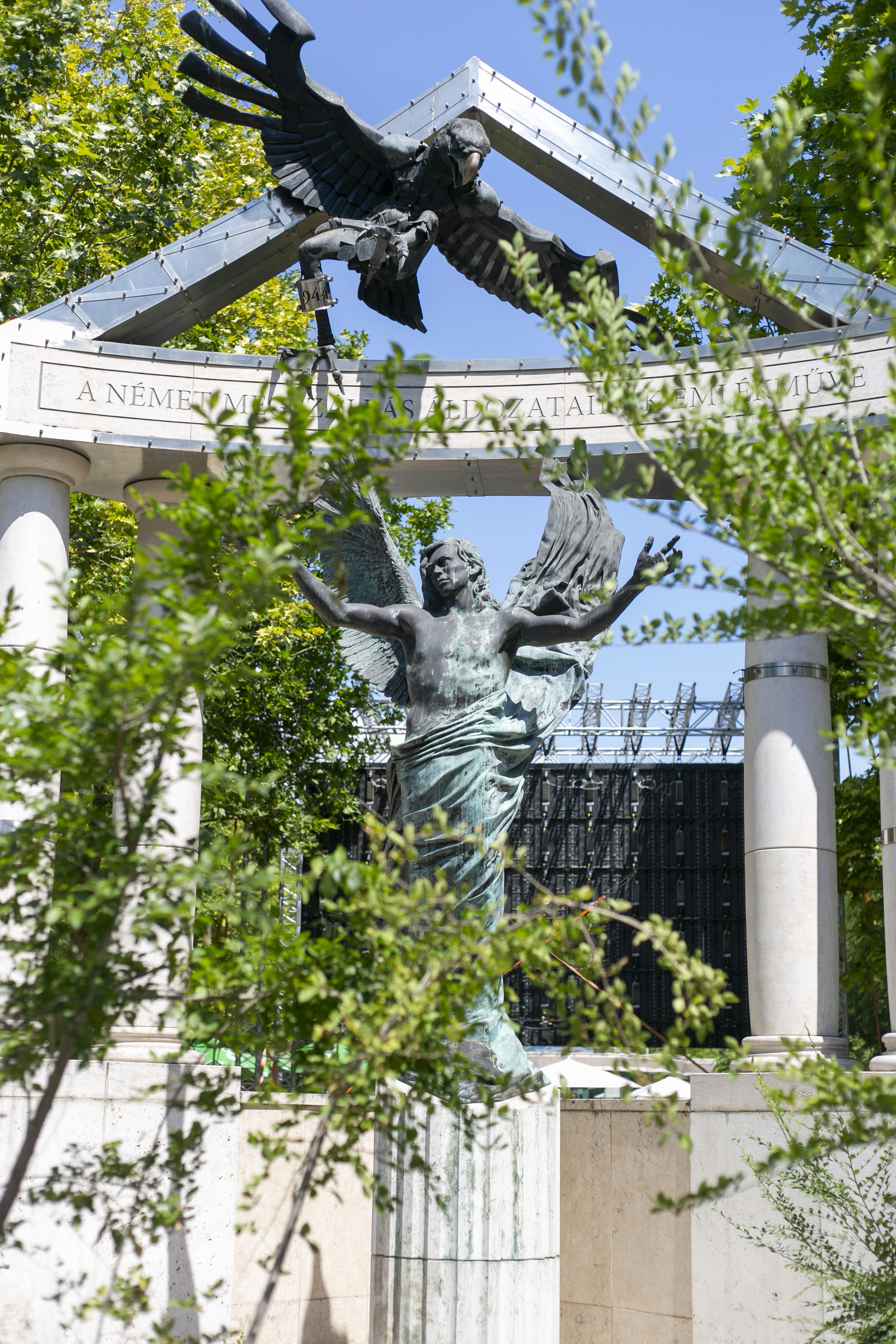 A bronze statue of an winged figure under a stone archway in Budapest