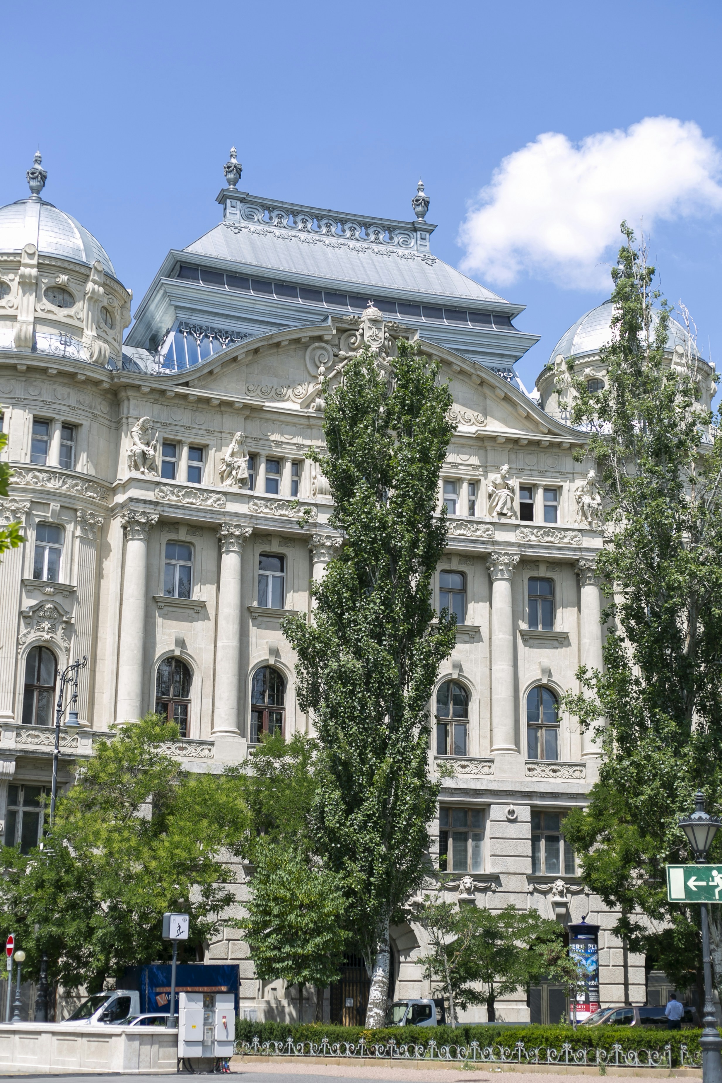 The ornate facade of the Gresham Palace in Budapest with tall green trees