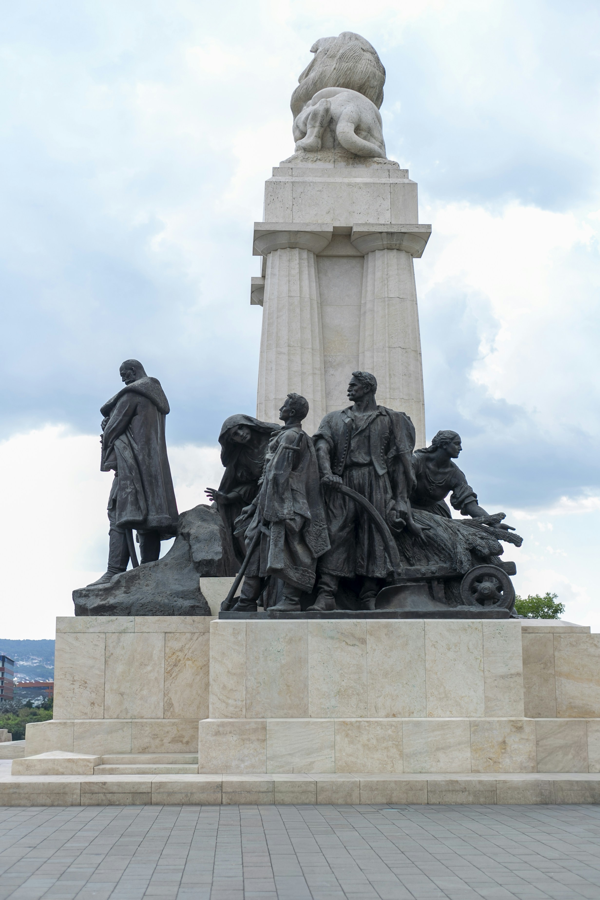 Bronze statues of people on a stone pedestal beneath a carved lion sculpture