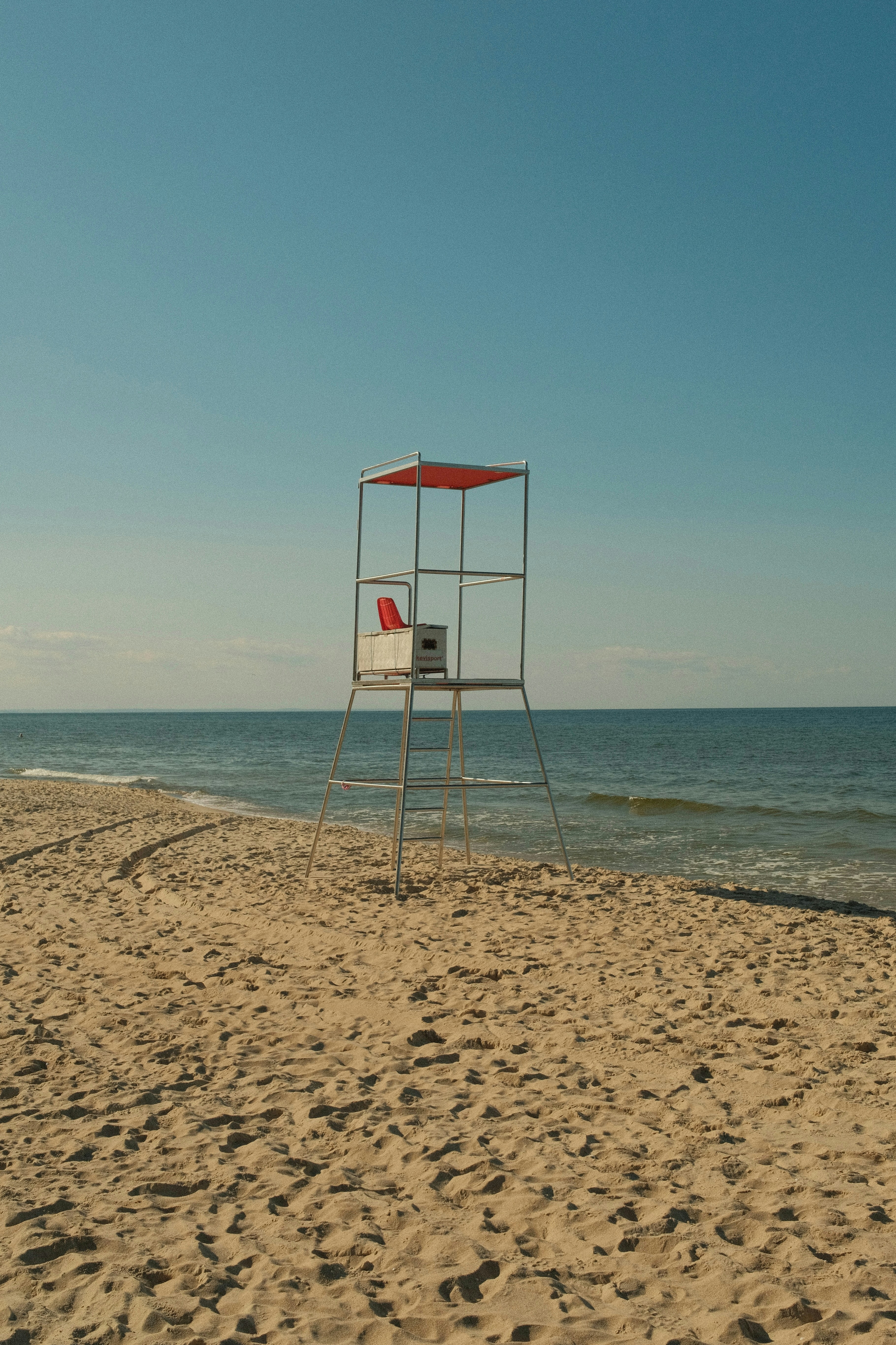 A metal lifeguard chair on a sandy beach by the ocean