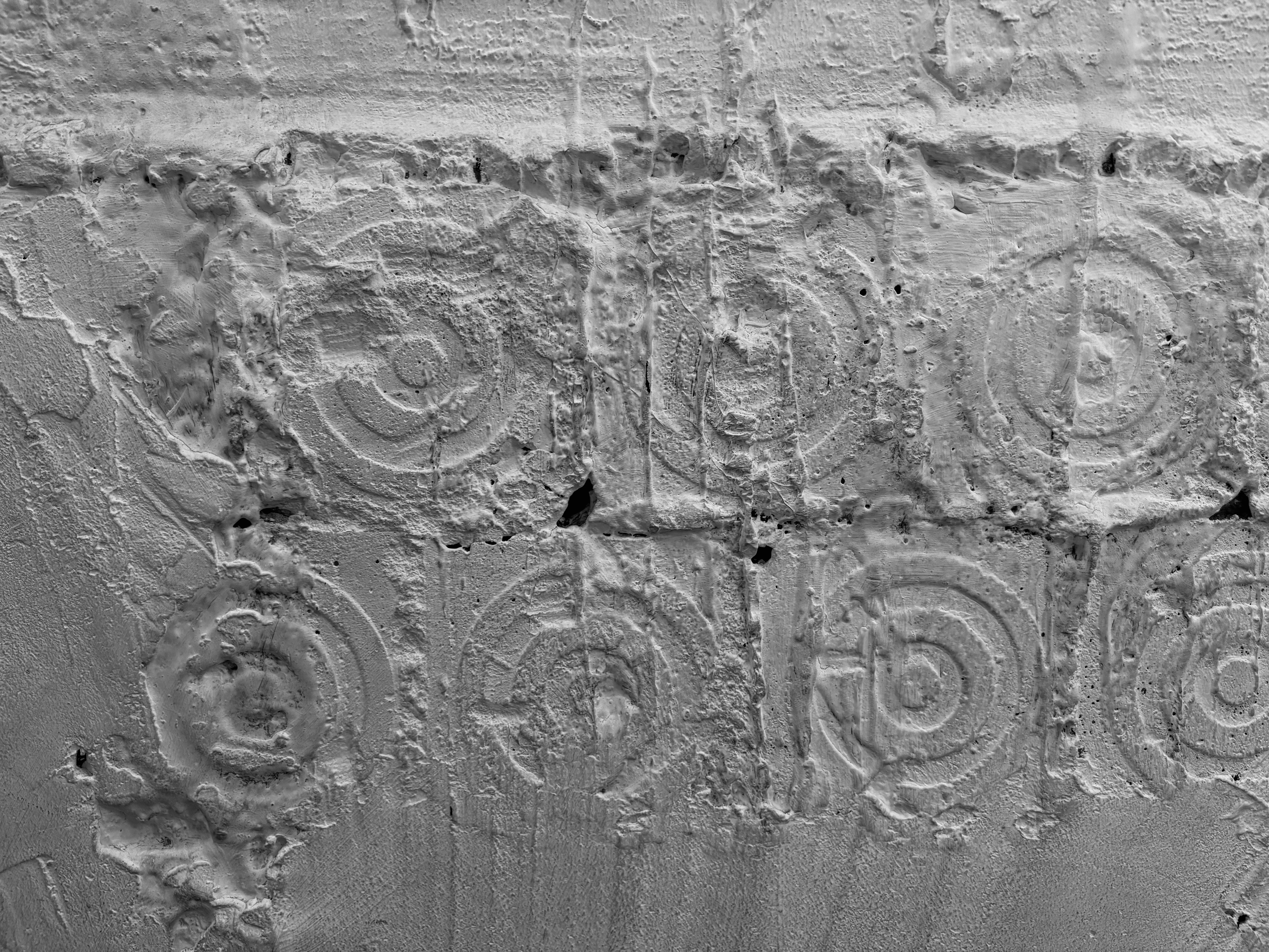 A grey concrete wall with a repeating pattern of embossed concentric circles