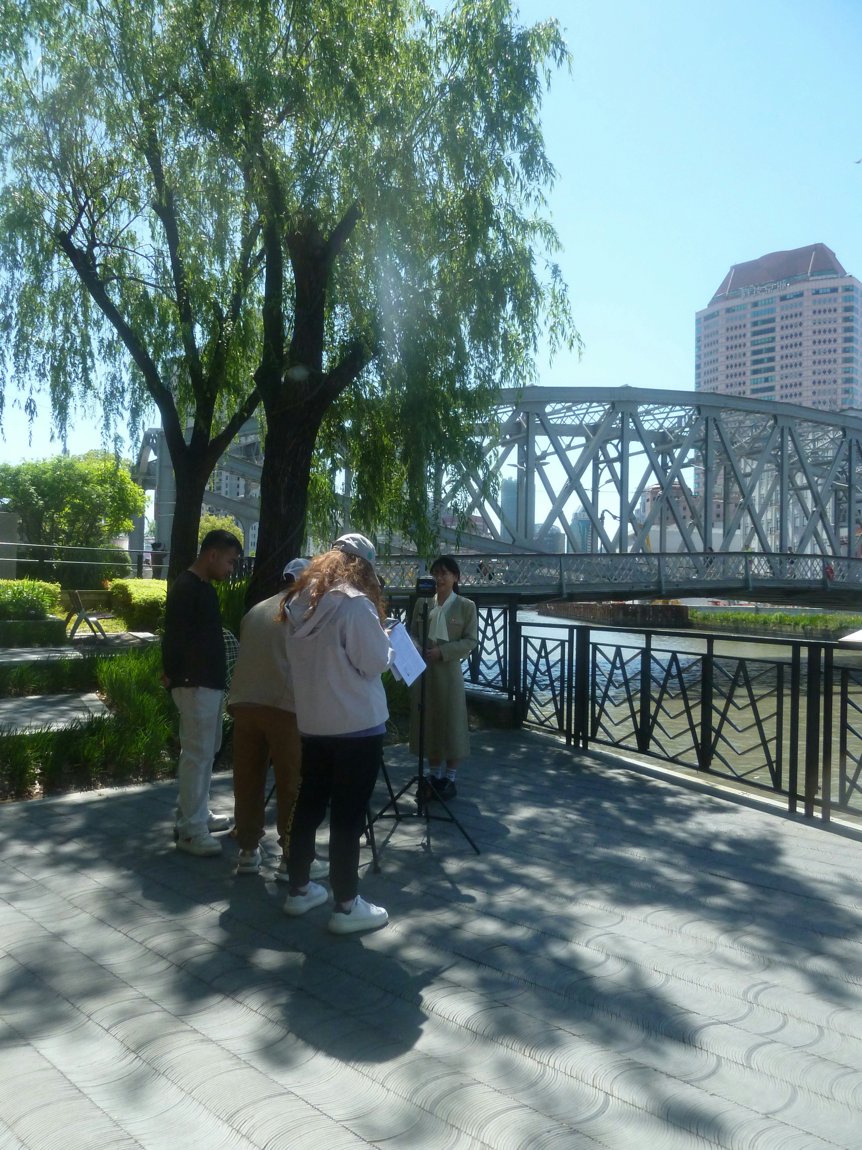 A group of people filming a woman near a metal bridge in Shanghai