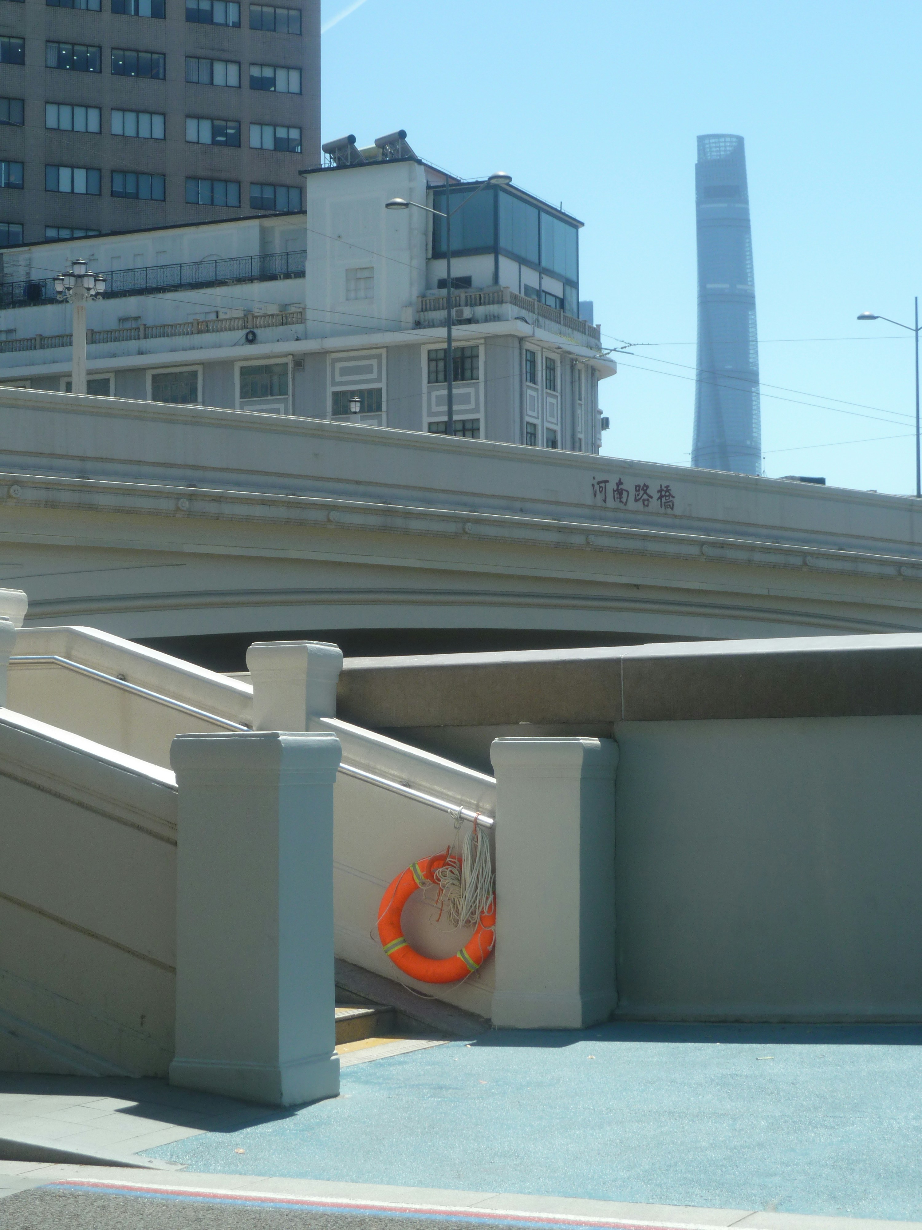 An orange life ring hanging on a concrete bridge railing in Shanghai