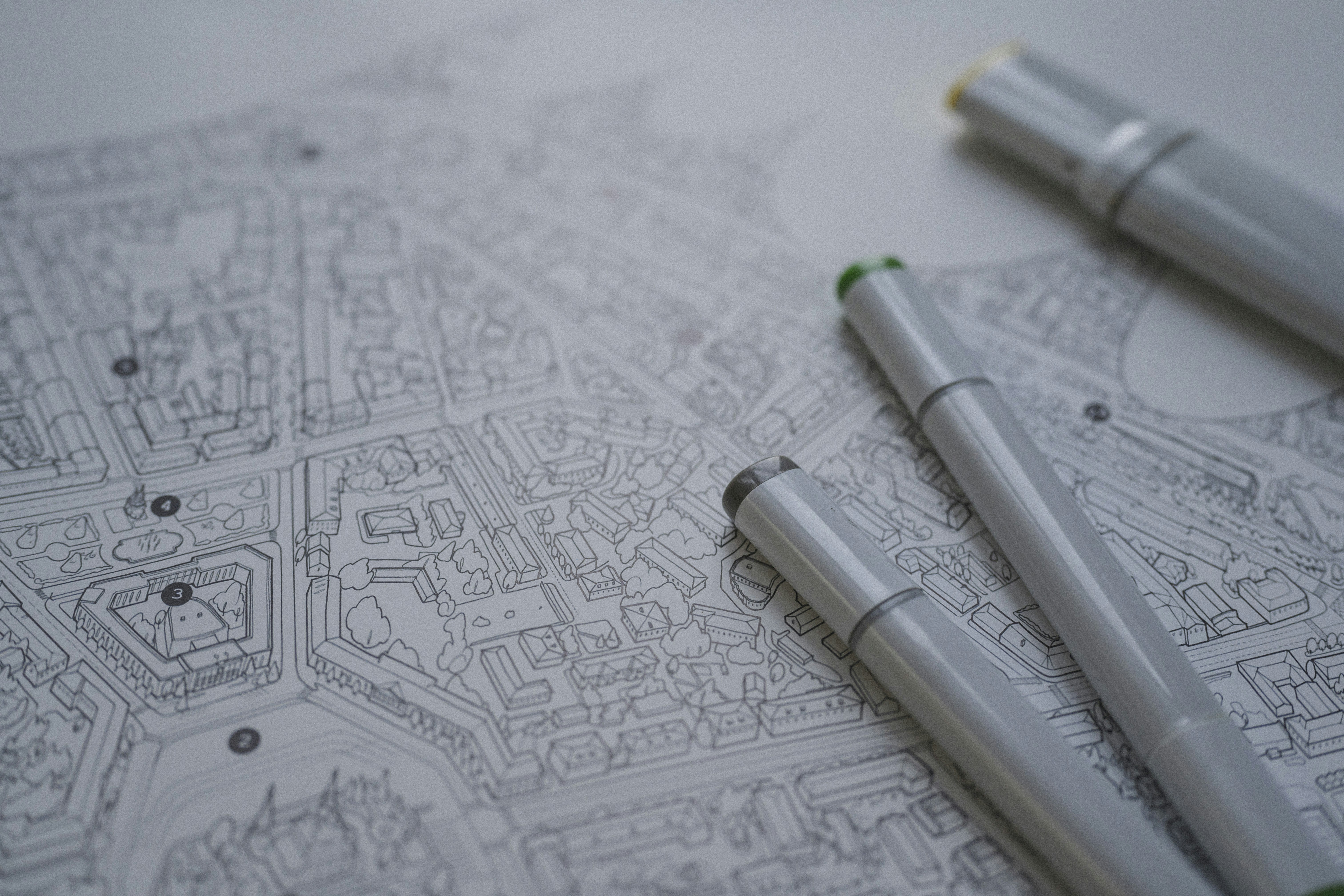 Three grey markers resting on a detailed black and white city map