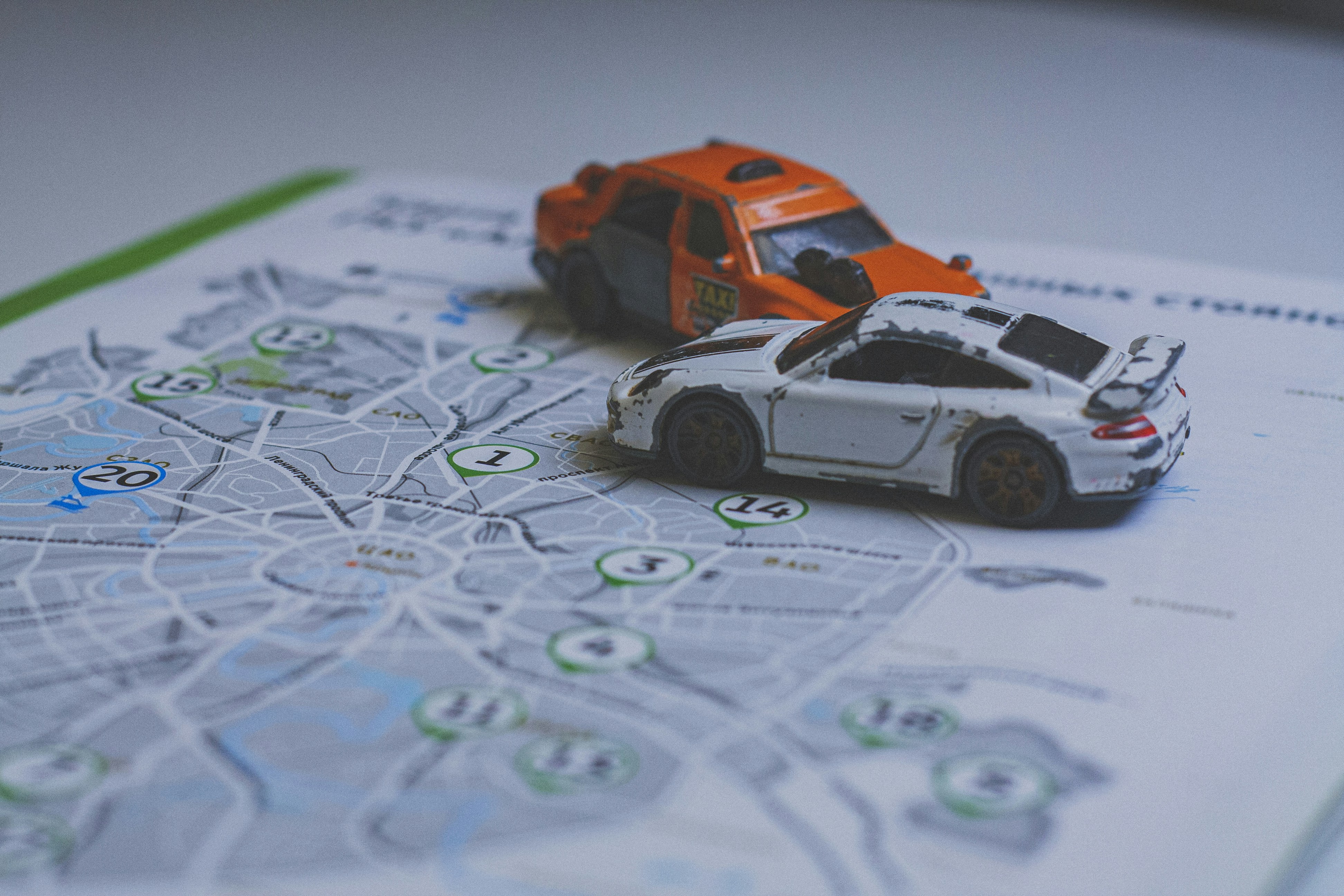 An orange taxi and a white sports car toy on a city map