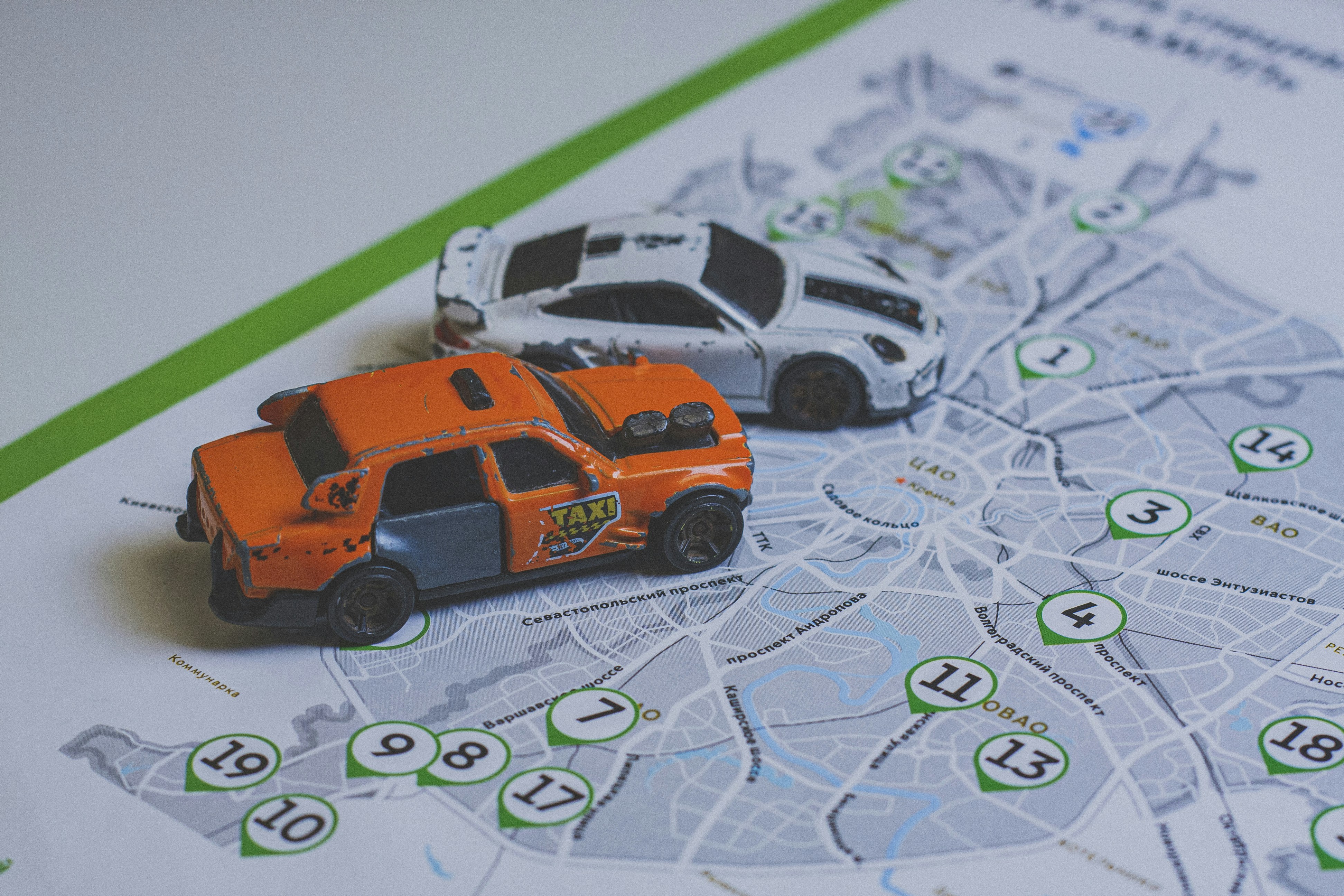 An orange taxi toy car and a white sports car on a city map