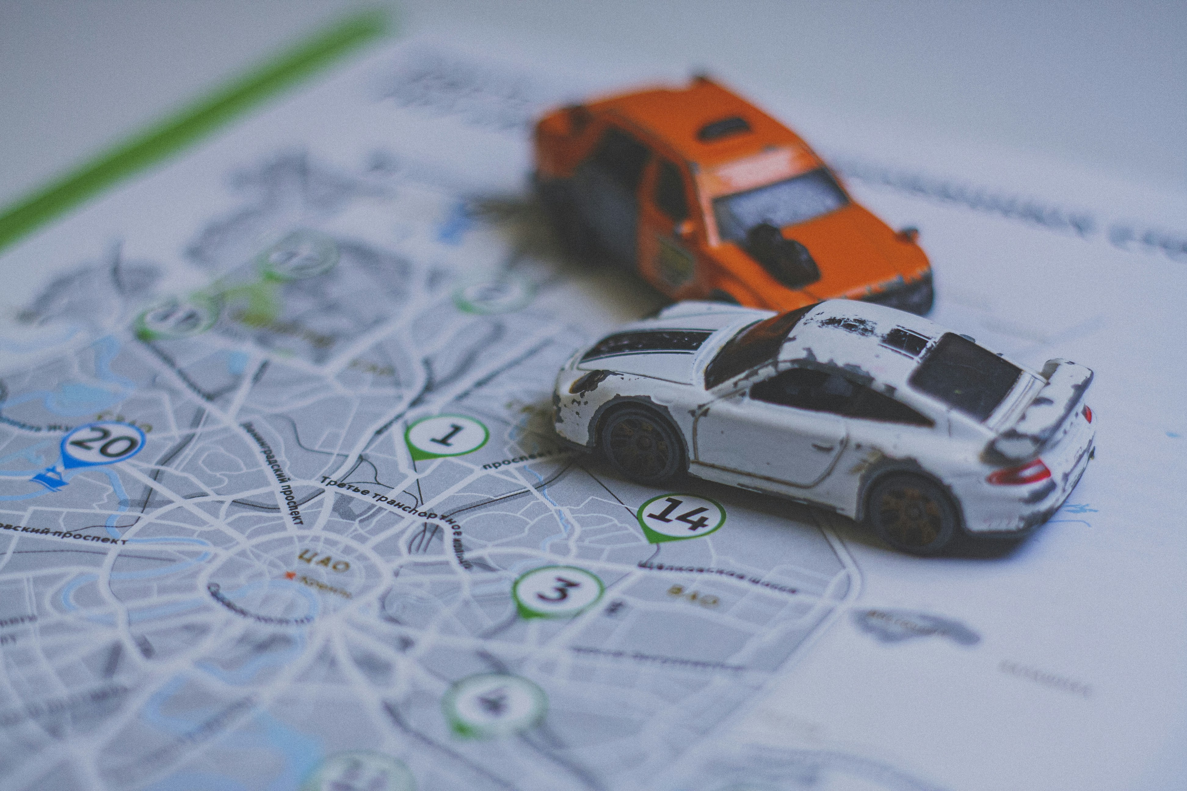 An orange toy car and a white toy sports car on a map