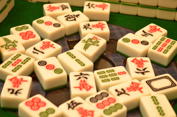 Close-up of mahjong tiles with red and green characters on green felt