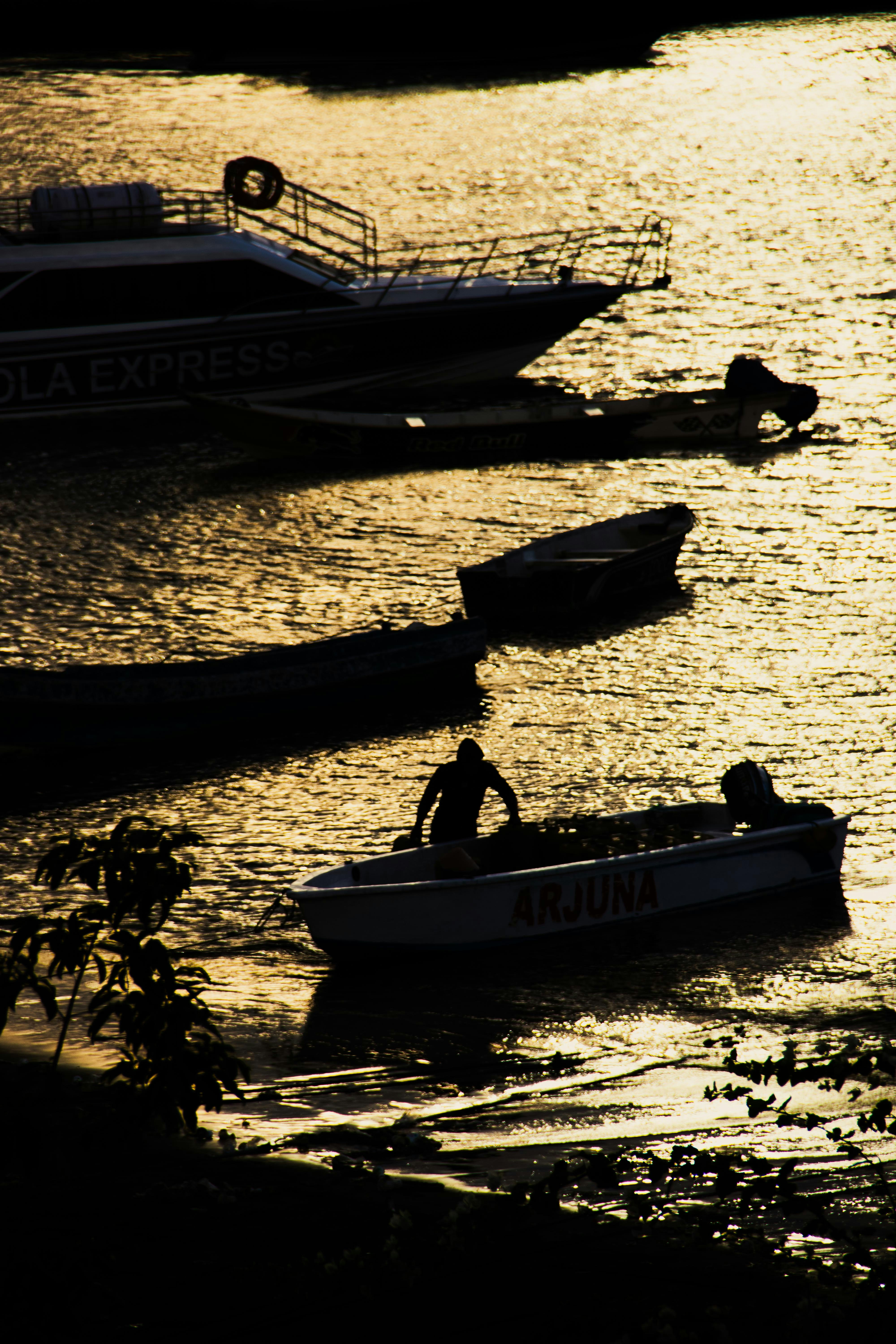 A person in a boat named Arjuna on shimmering water at golden hour
