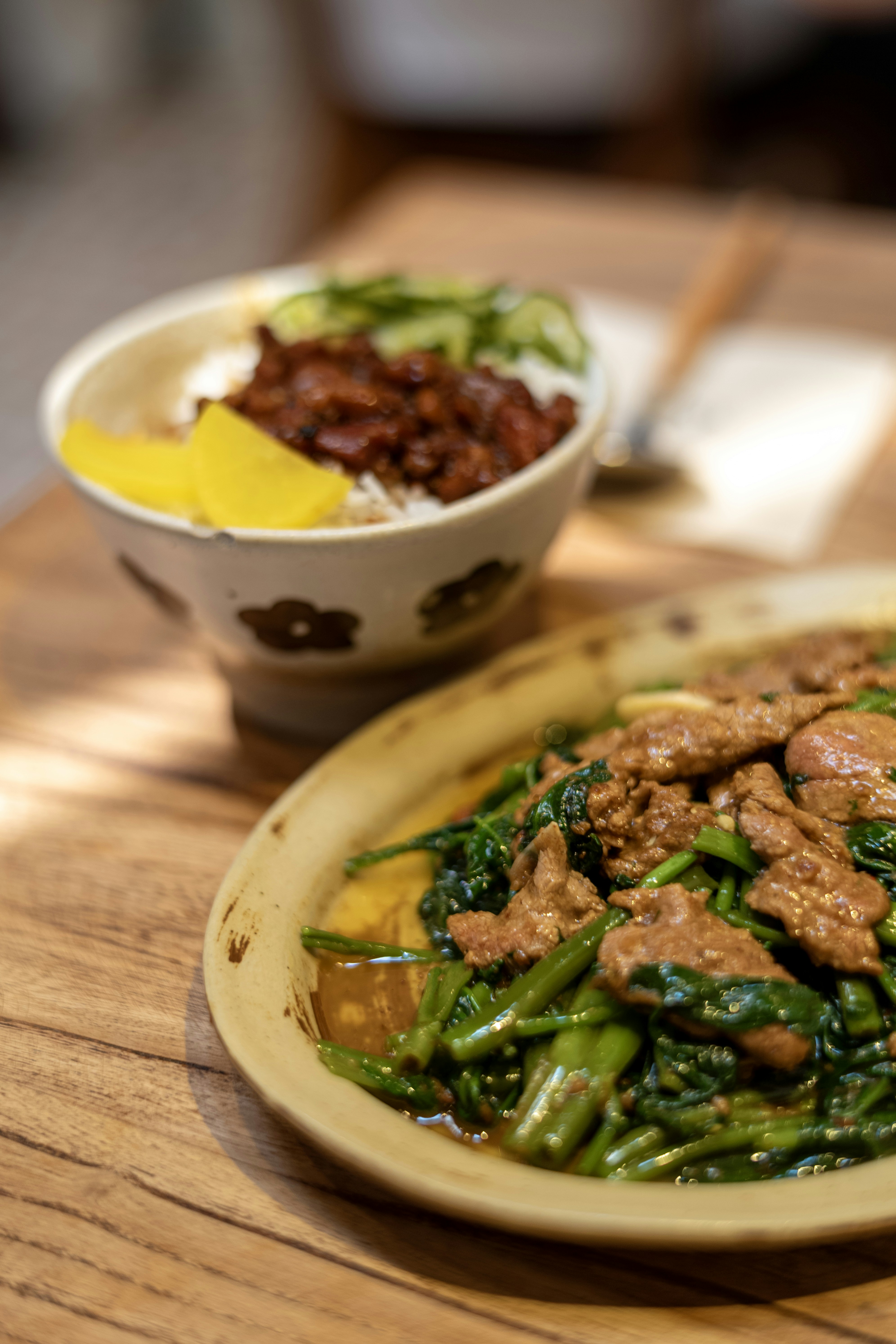 Stir-fried beef with water spinach and a bowl of rice on a wooden table