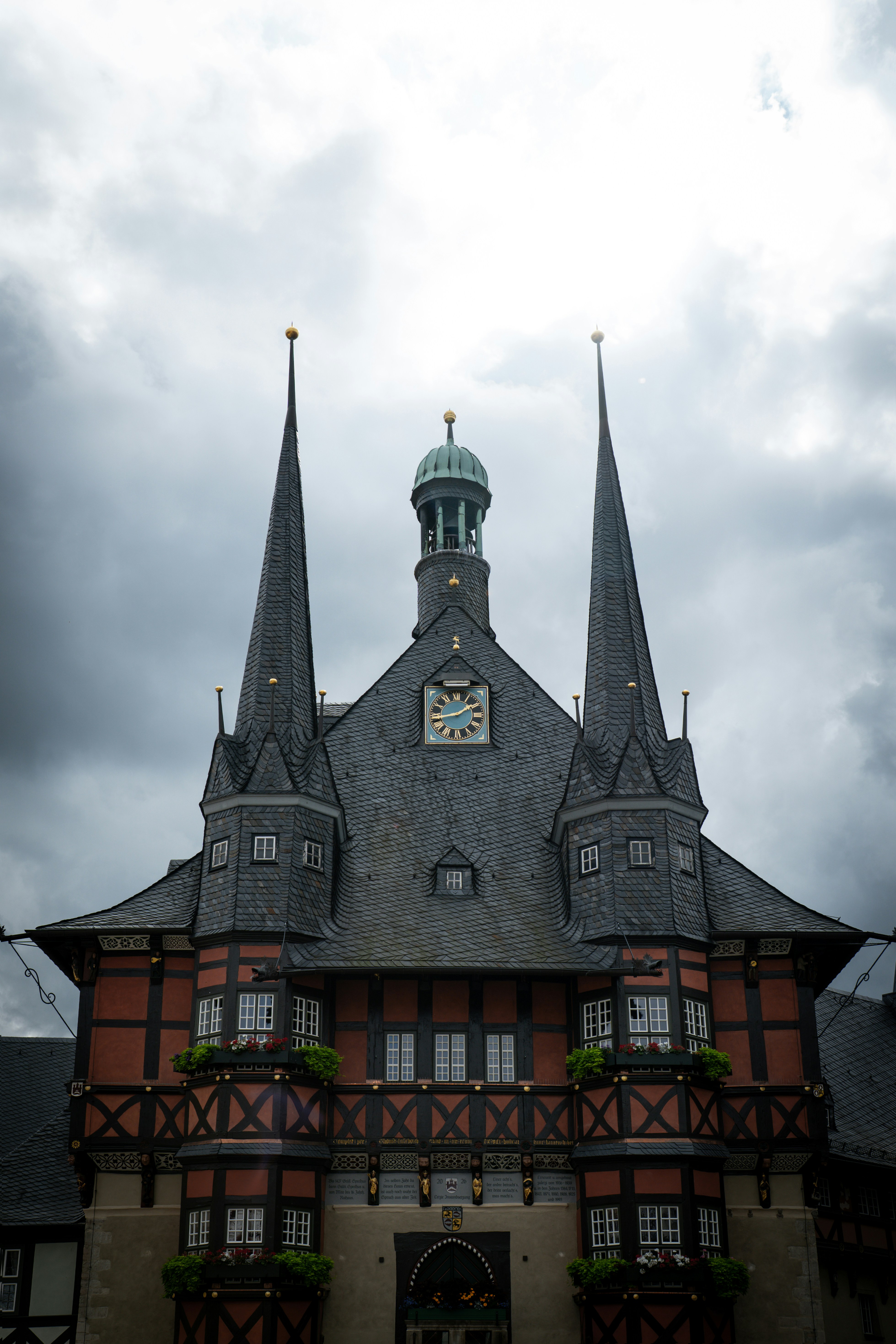 The Wernigerode Town Hall with two tall spires under a cloudy sky