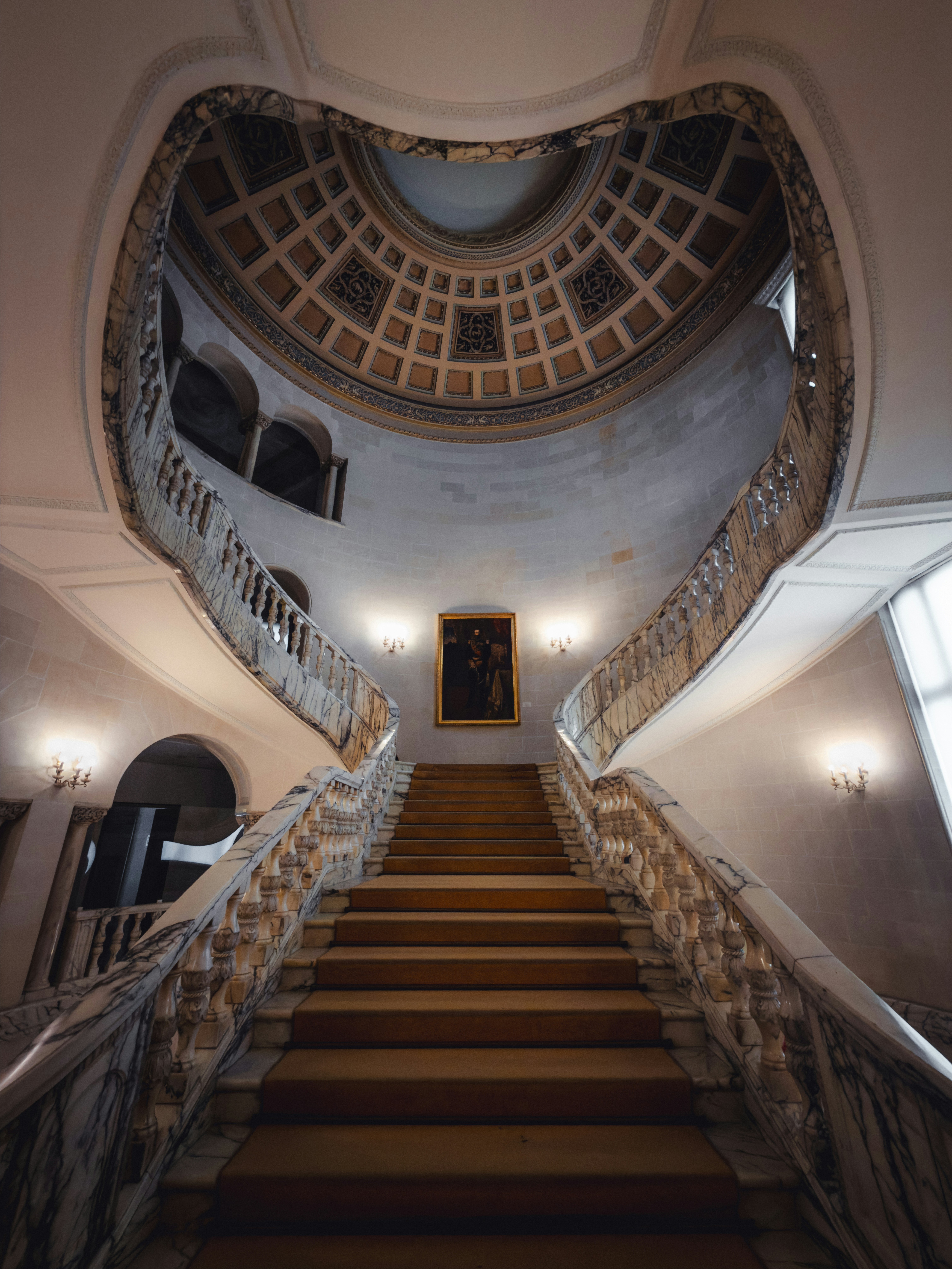 A grand marble staircase with a carpeted runner in a building in Bucharest