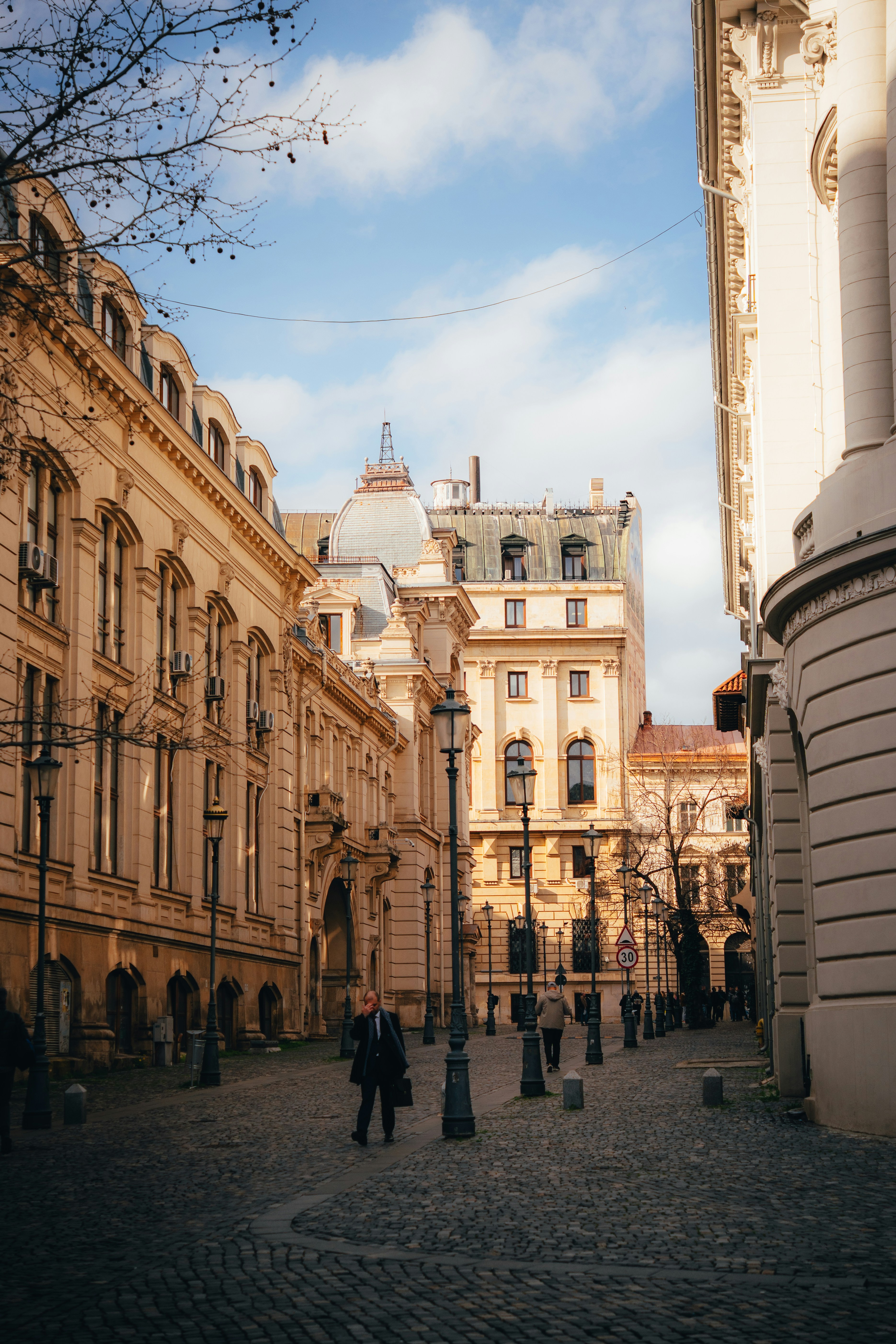 People walking on a cobblestone street between historic buildings in a city
