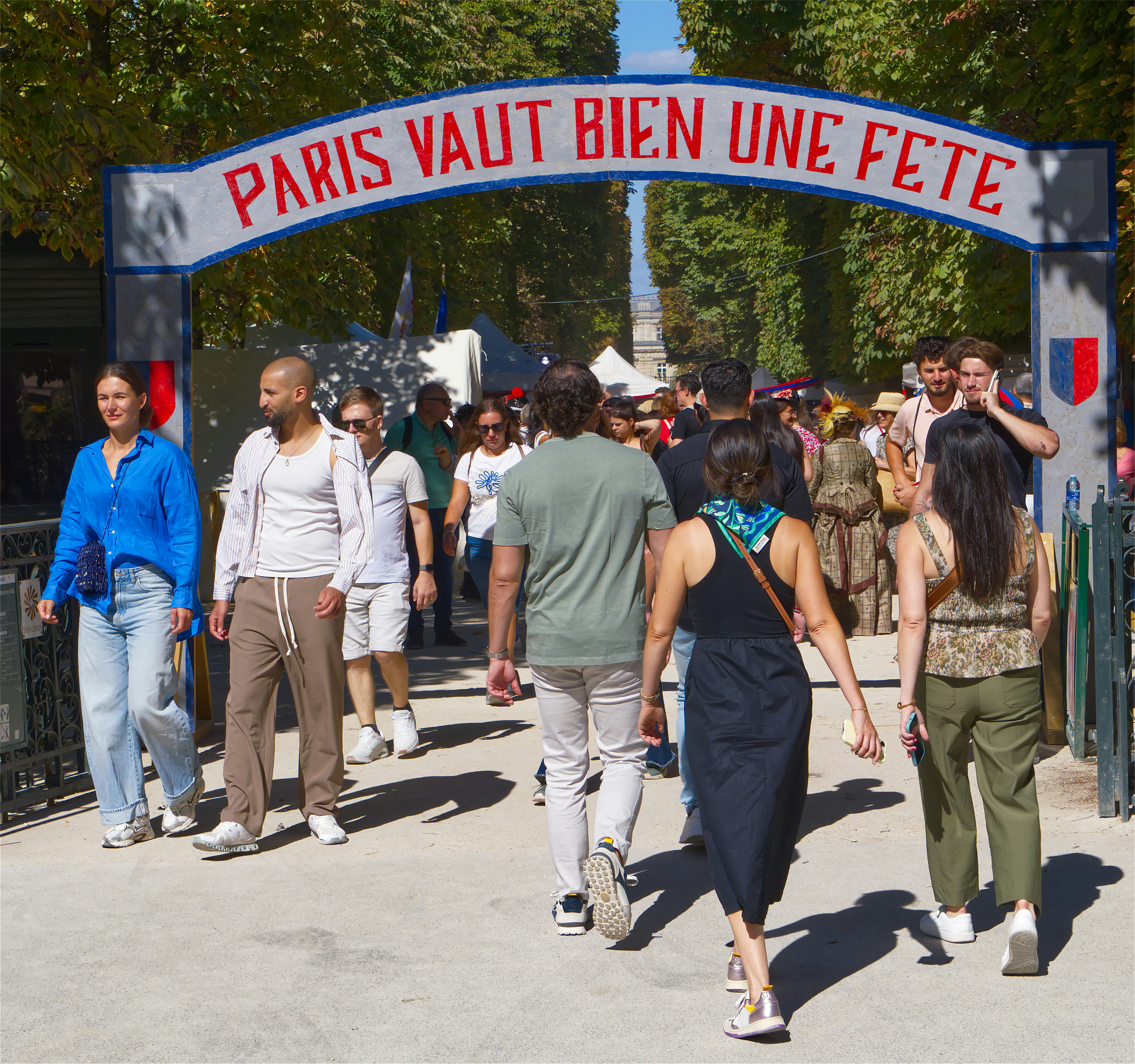 People walking under an archway reading PARIS VAUT BIEN UNE FETE in Paris