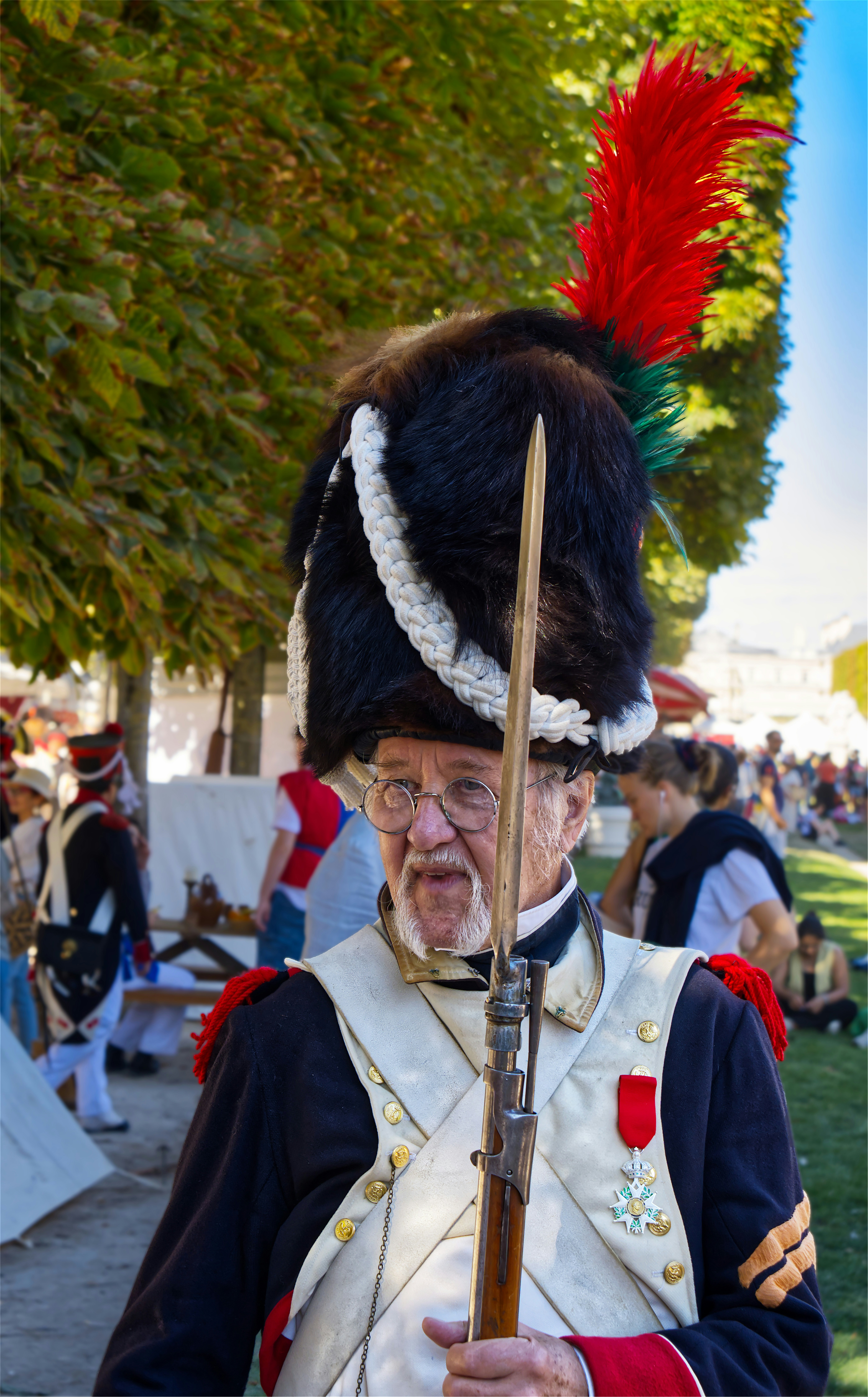 A man in a historical military uniform with a tall fur hat and musket