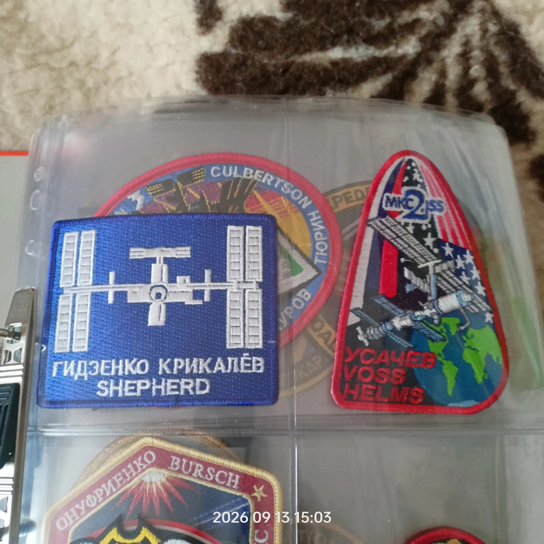 Embroidered International Space Station crew patches in the clear pockets of a binder page