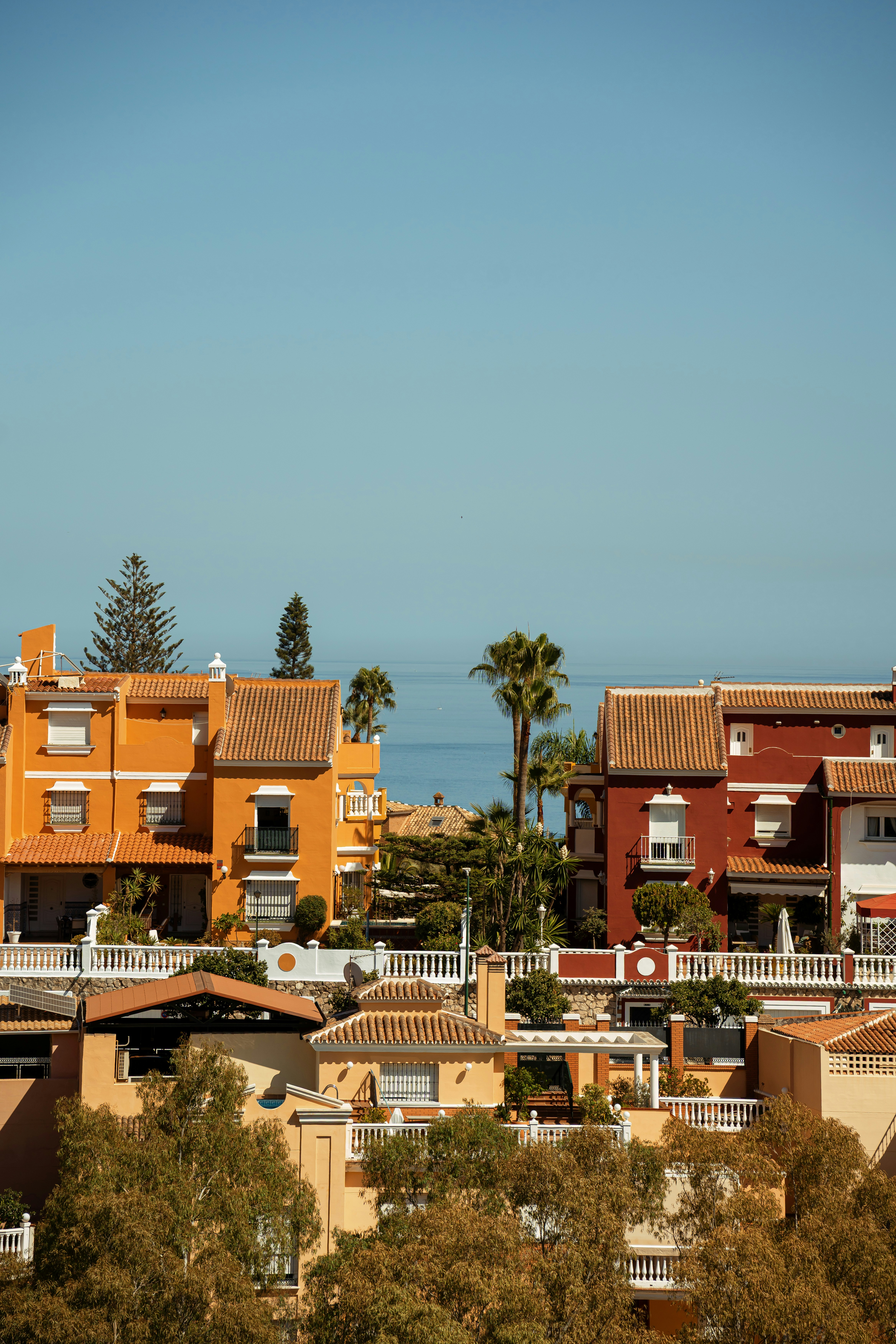 Orange and red Mediterranean houses with tiled roofs overlooking the blue sea