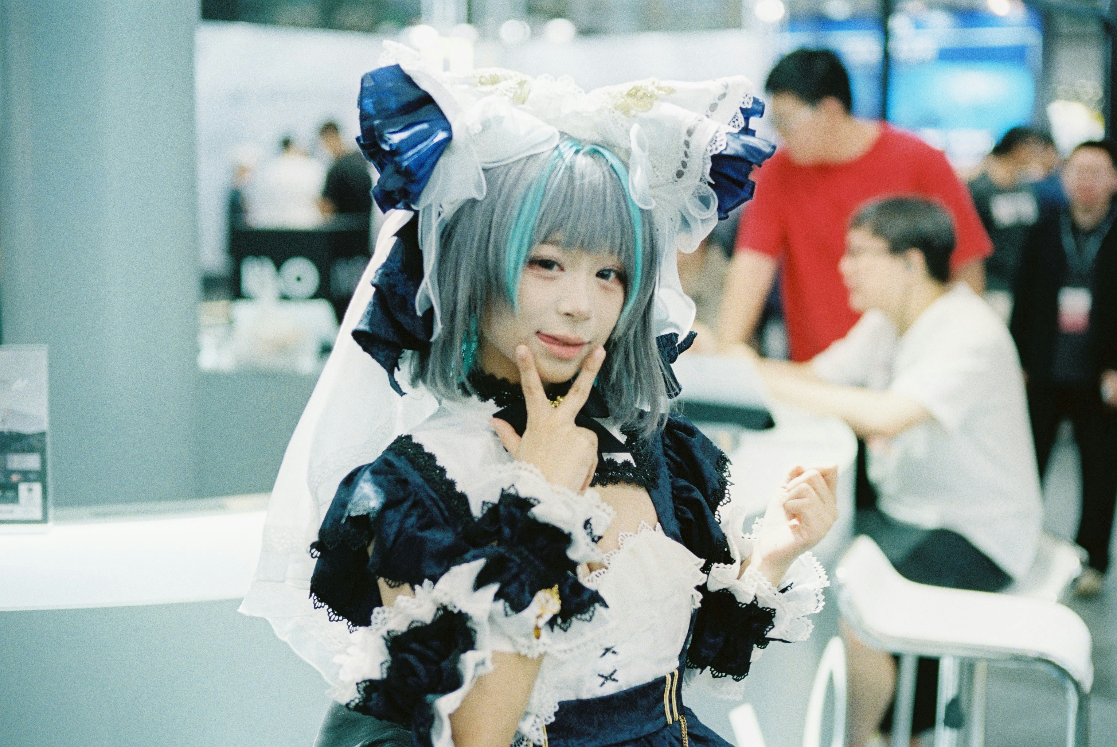 A person in a frilly blue and white costume making a peace sign