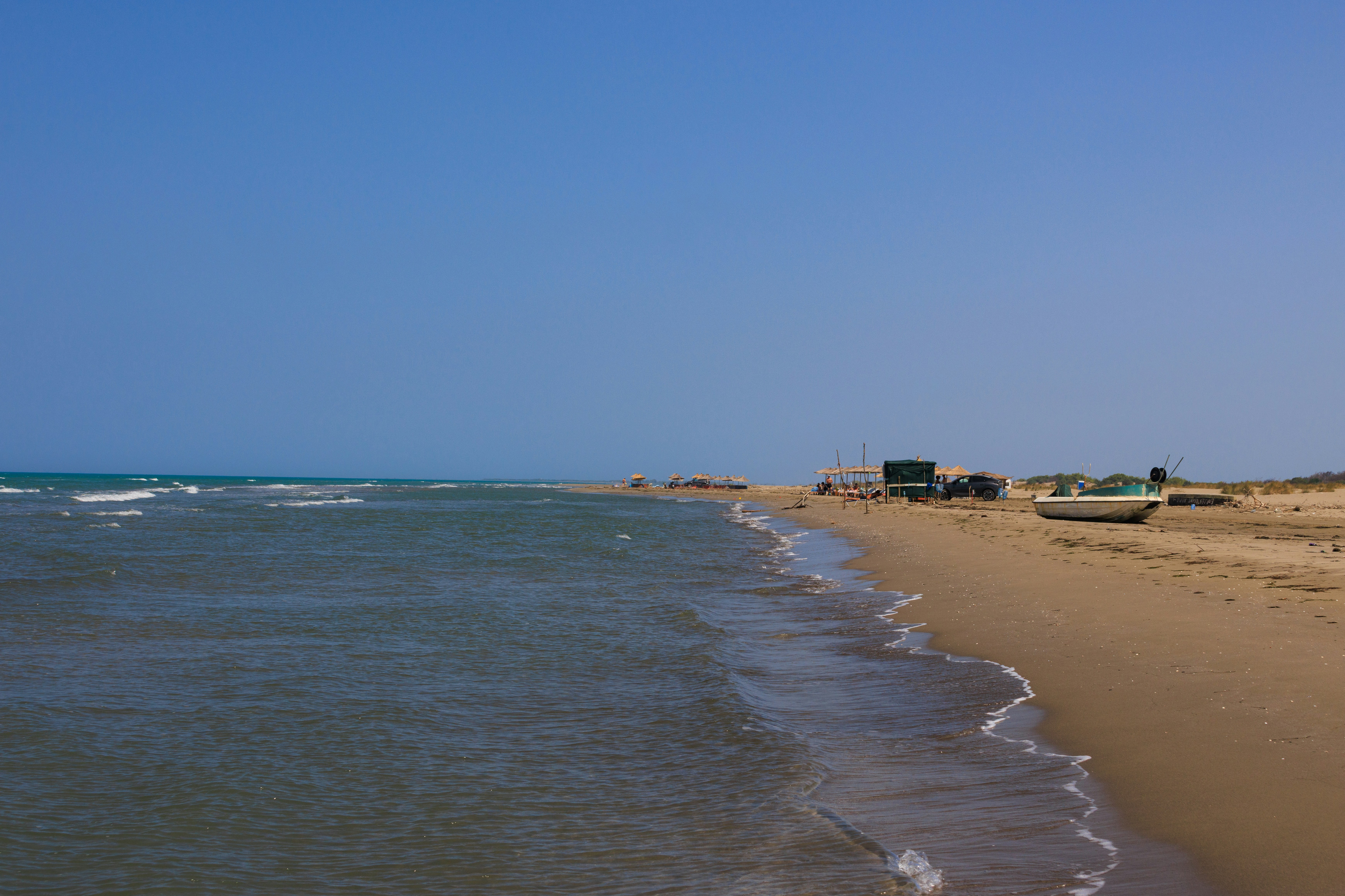 A small boat on a sandy beach beside the calm blue sea