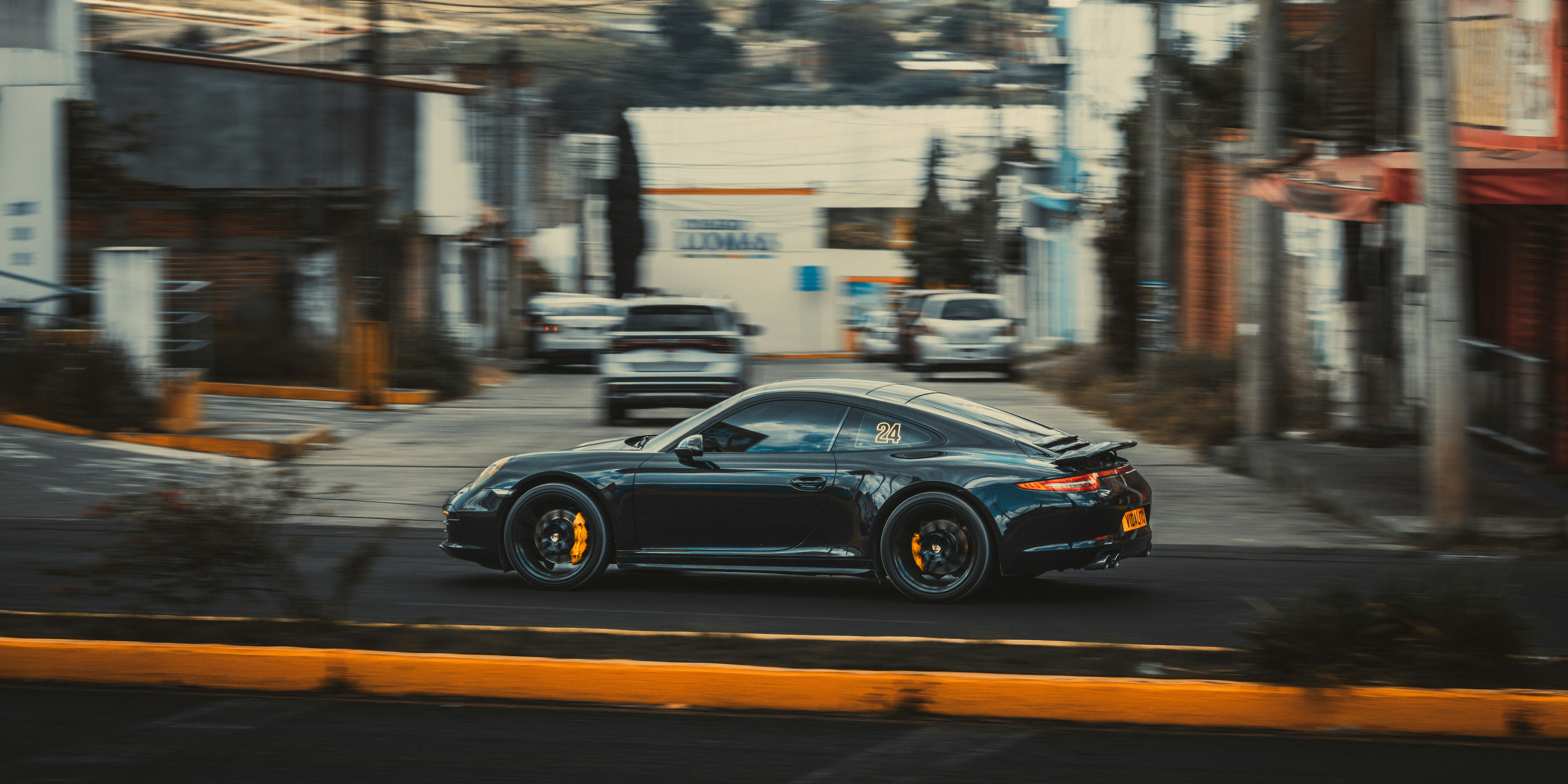 A black sports car driving fast on a city street with motion blur