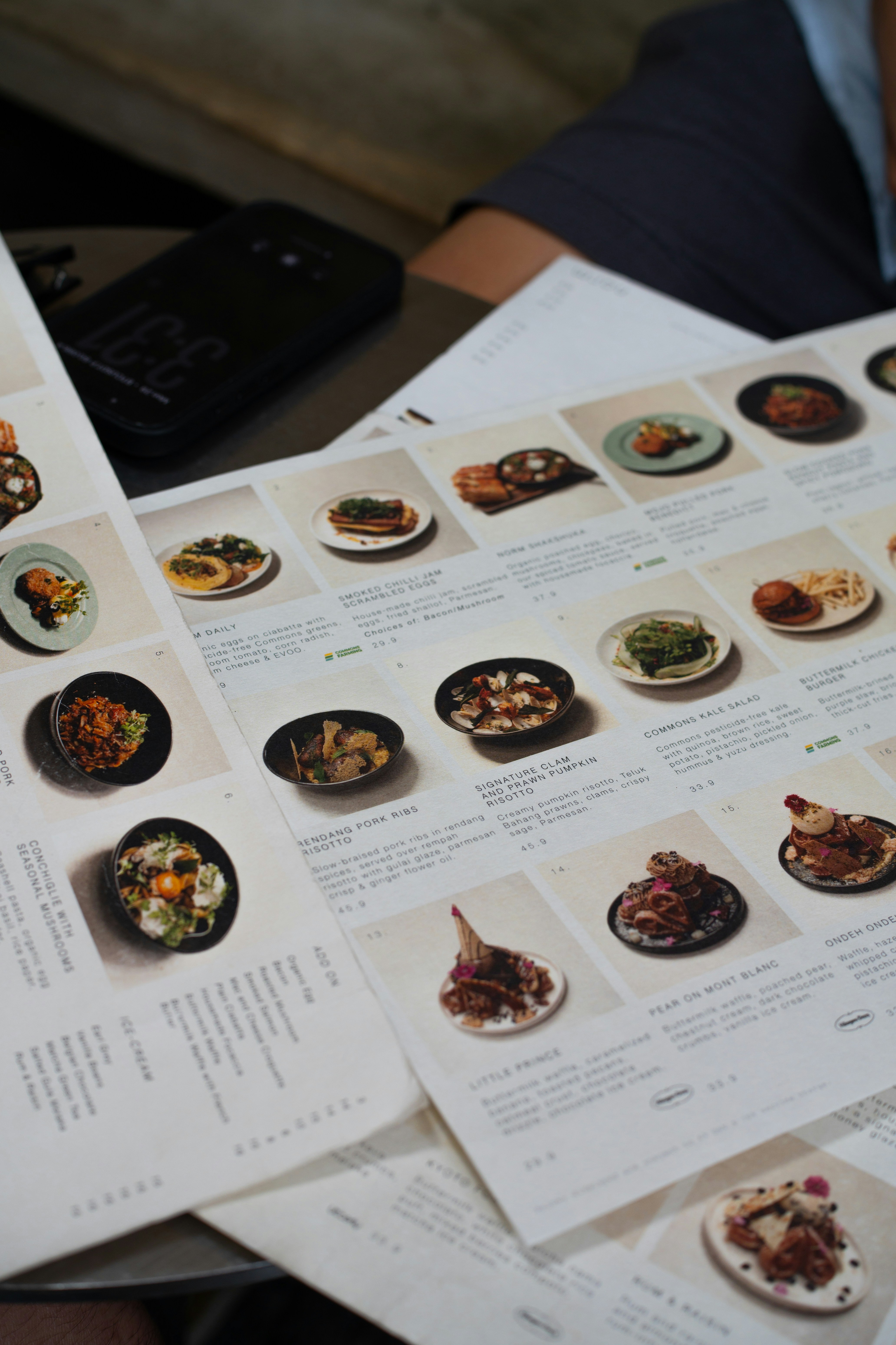 A restaurant menu with photographs of various dishes on a dark table