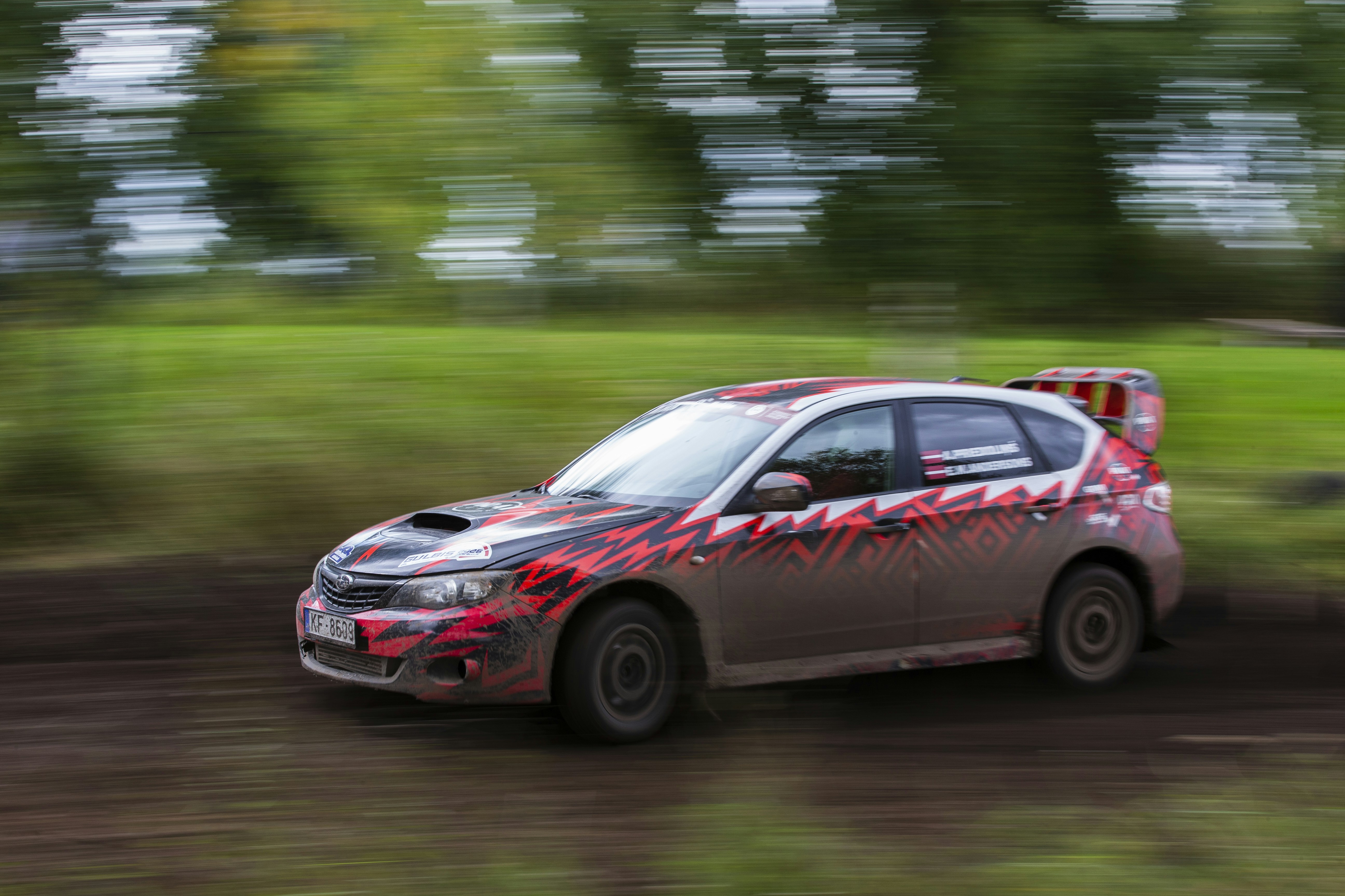 A rally car speeding along a dirt track with motion blur in the background