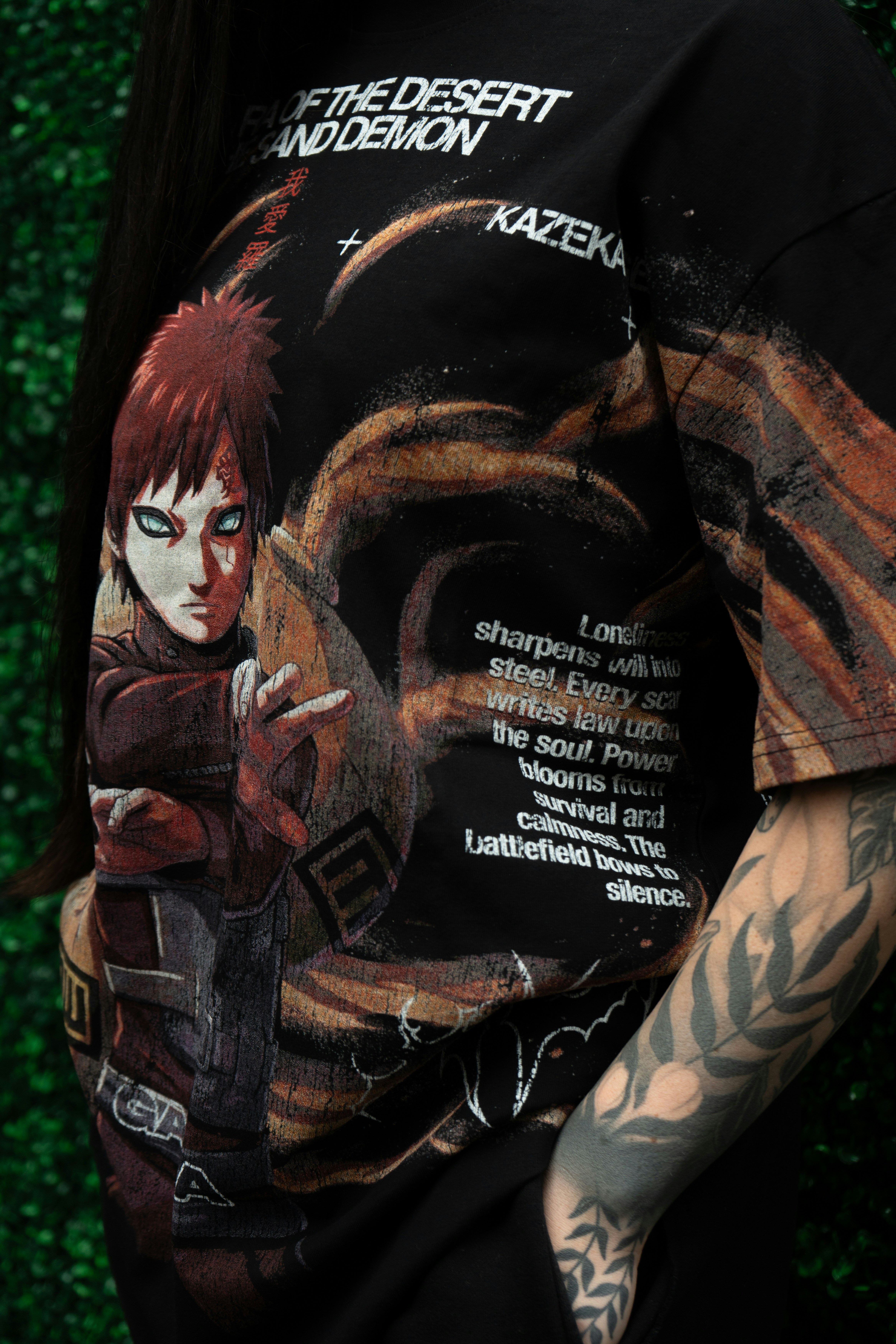 A person wearing a black t-shirt with an anime character print and text