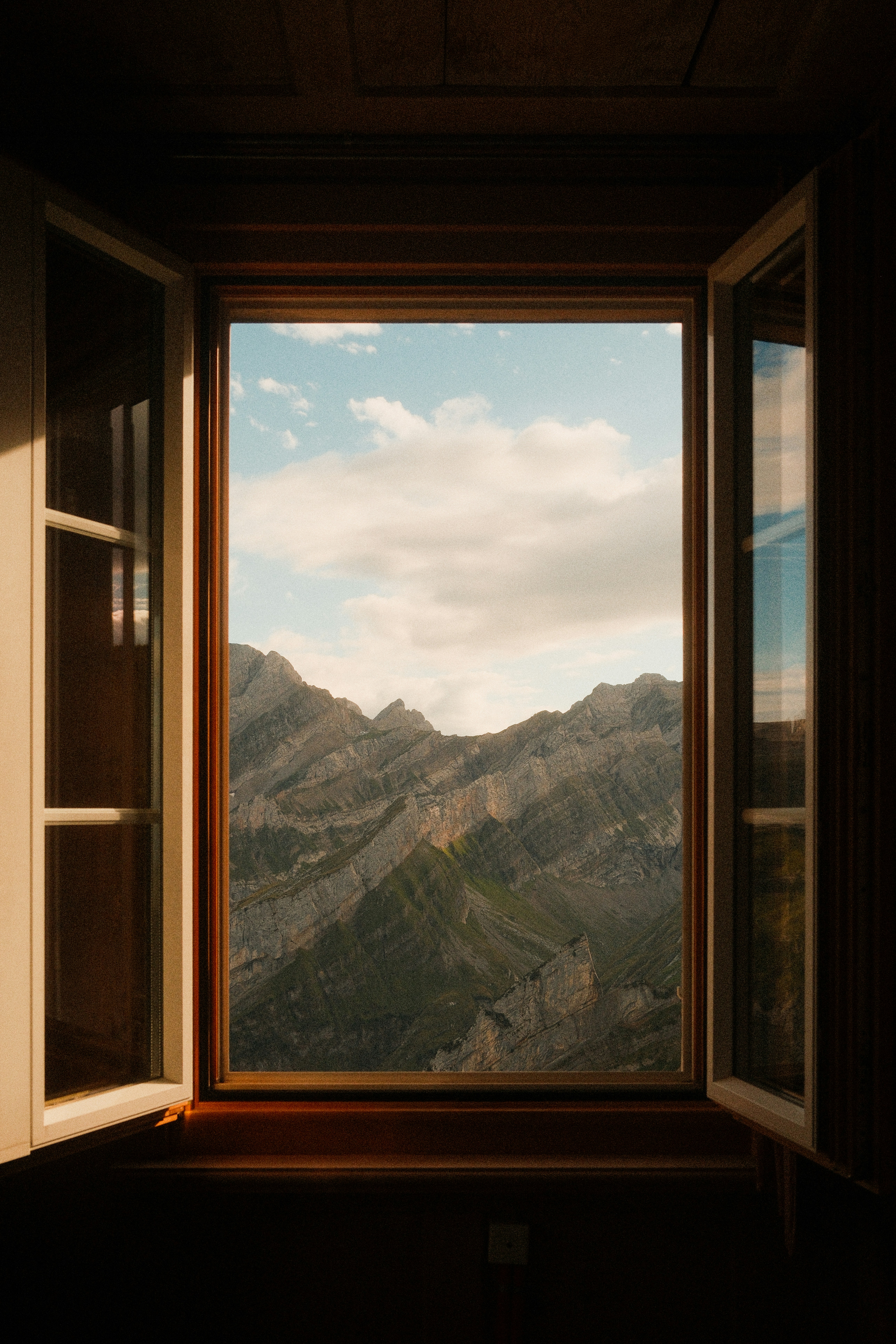 Open window frame looking out onto rugged mountain peaks in Switzerland