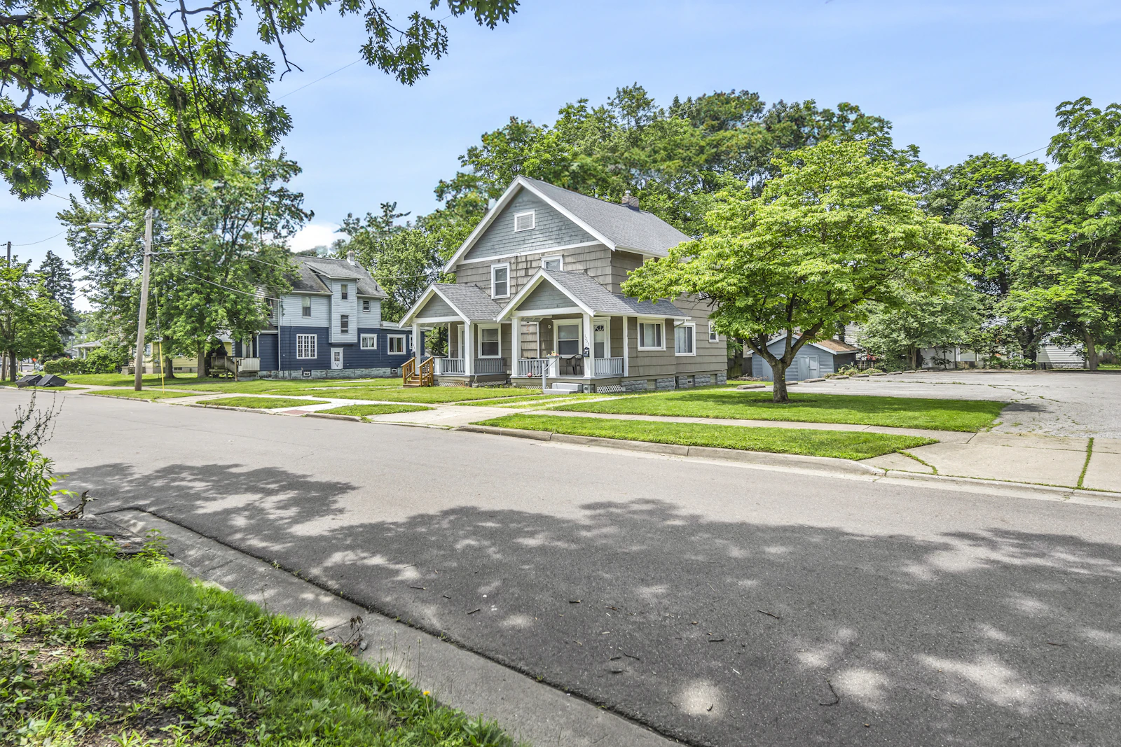 Residential street with two homes under a clear blue sky