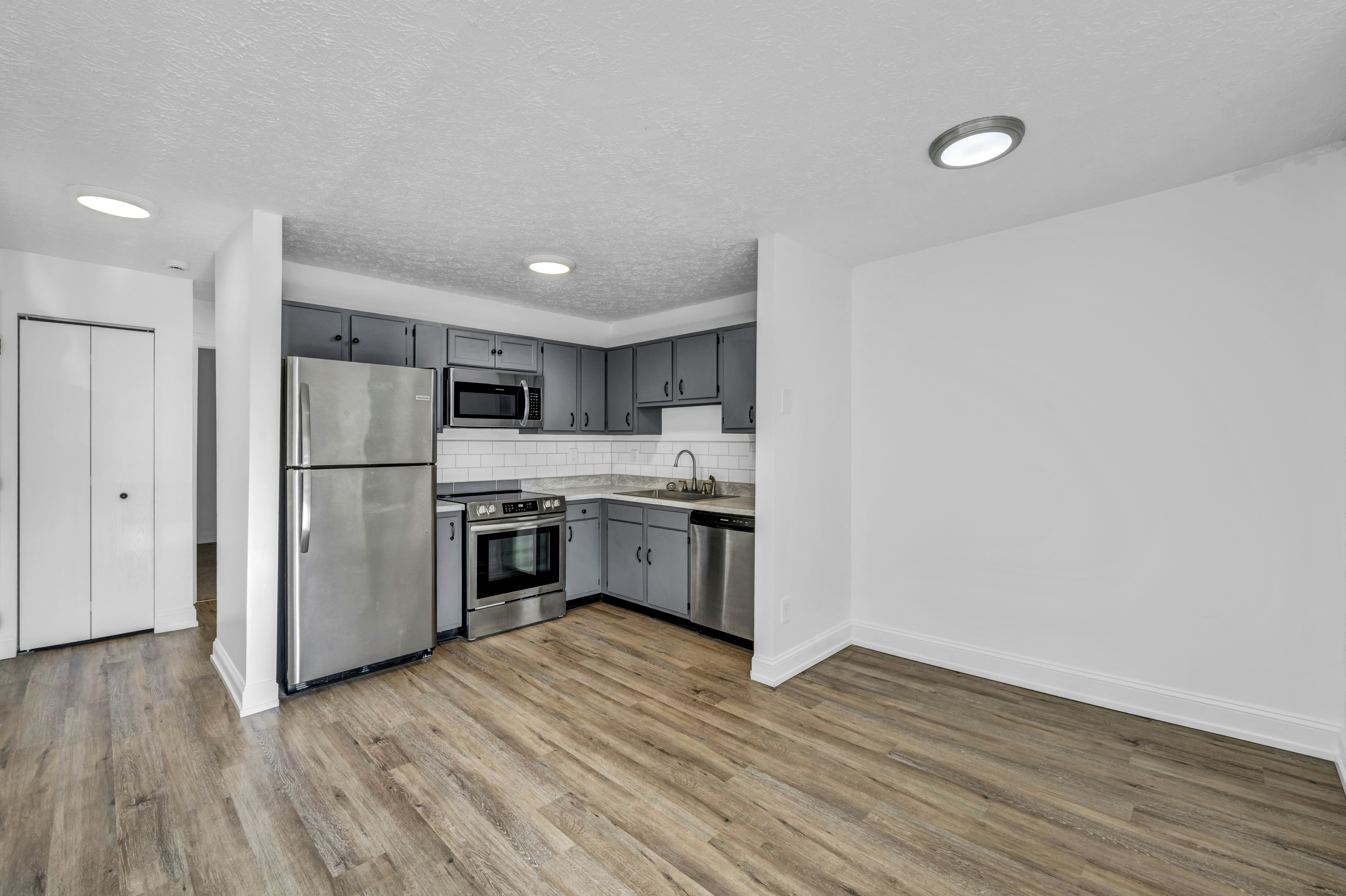 Empty kitchen with grey cabinets and stainless fridge