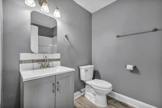 A bathroom with grey walls, a white vanity, and a white toilet