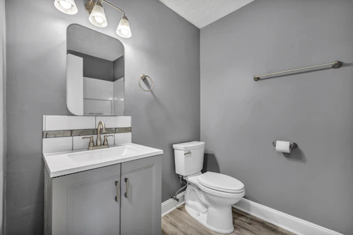 A bathroom with grey walls, a white vanity, and a white toilet