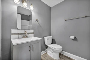 Bathroom with grey walls, a white vanity and a white toilet
