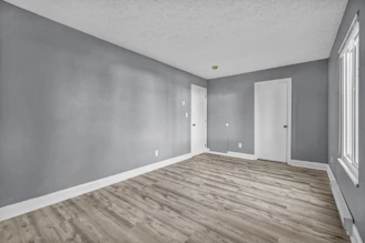 An empty room with grey walls, white doors, and light wood flooring