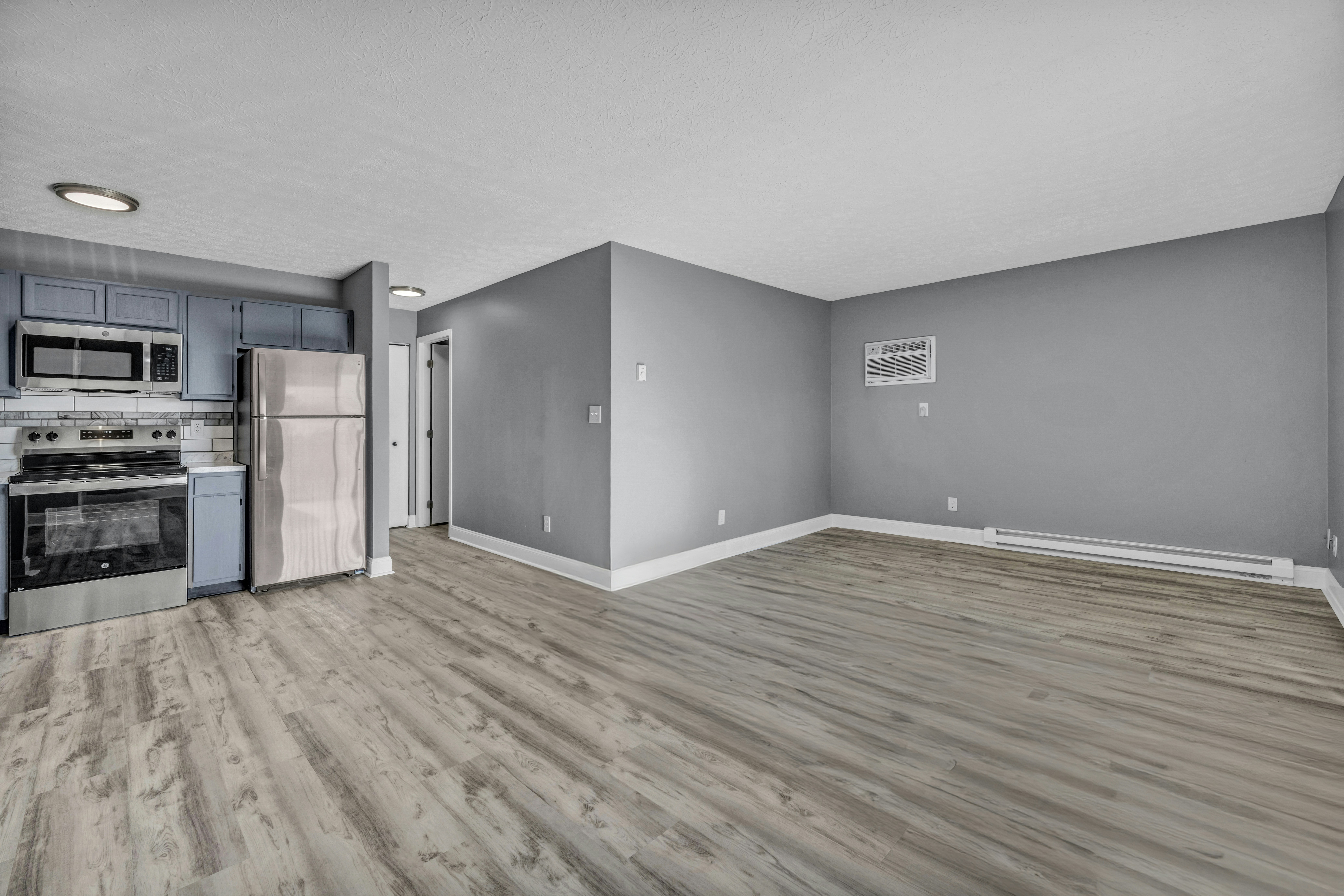 Empty apartment with a kitchen and open living area, appliances in place and floors cleaned for the next move-in