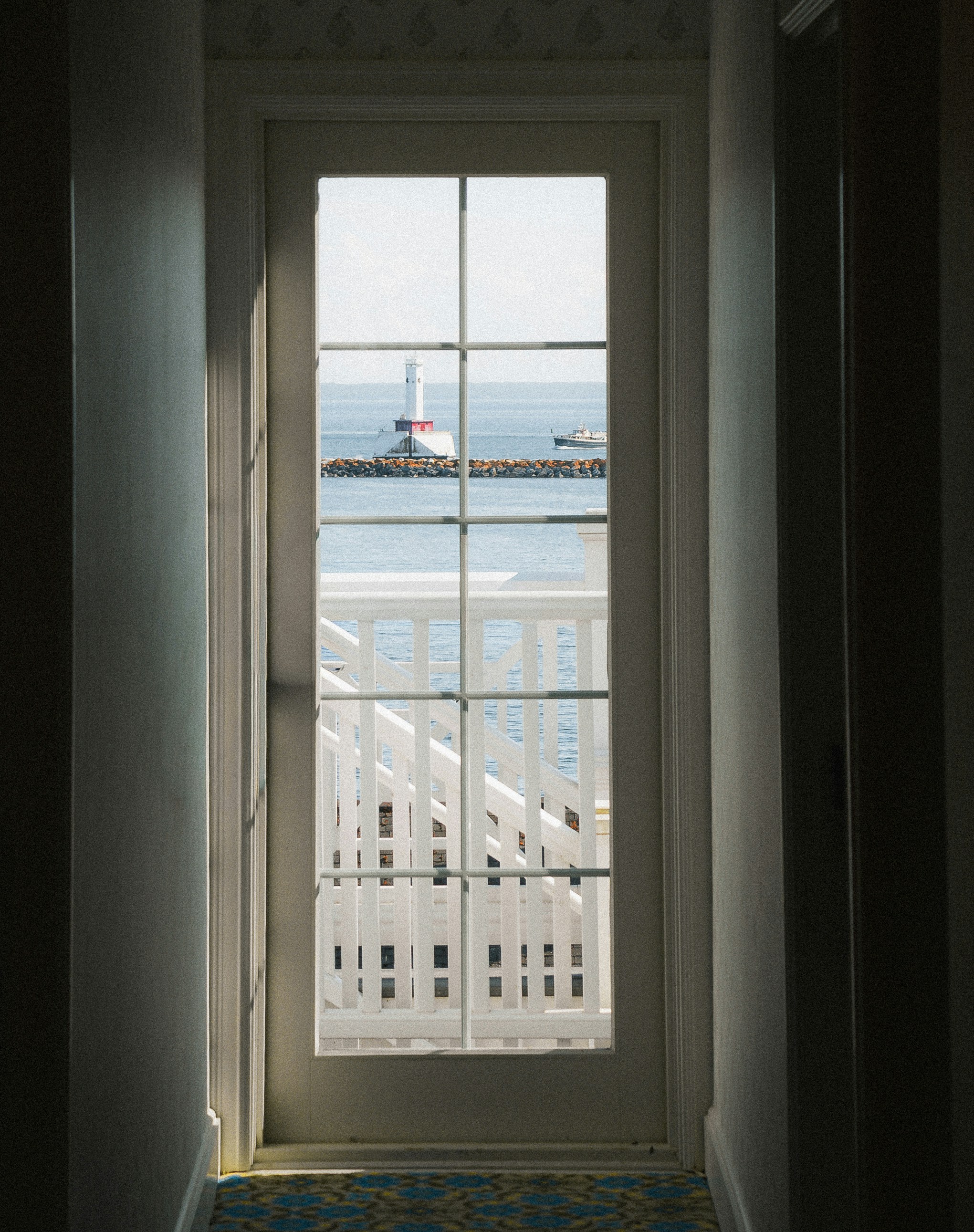 A view through a glass door of a lighthouse on a breakwater at sea