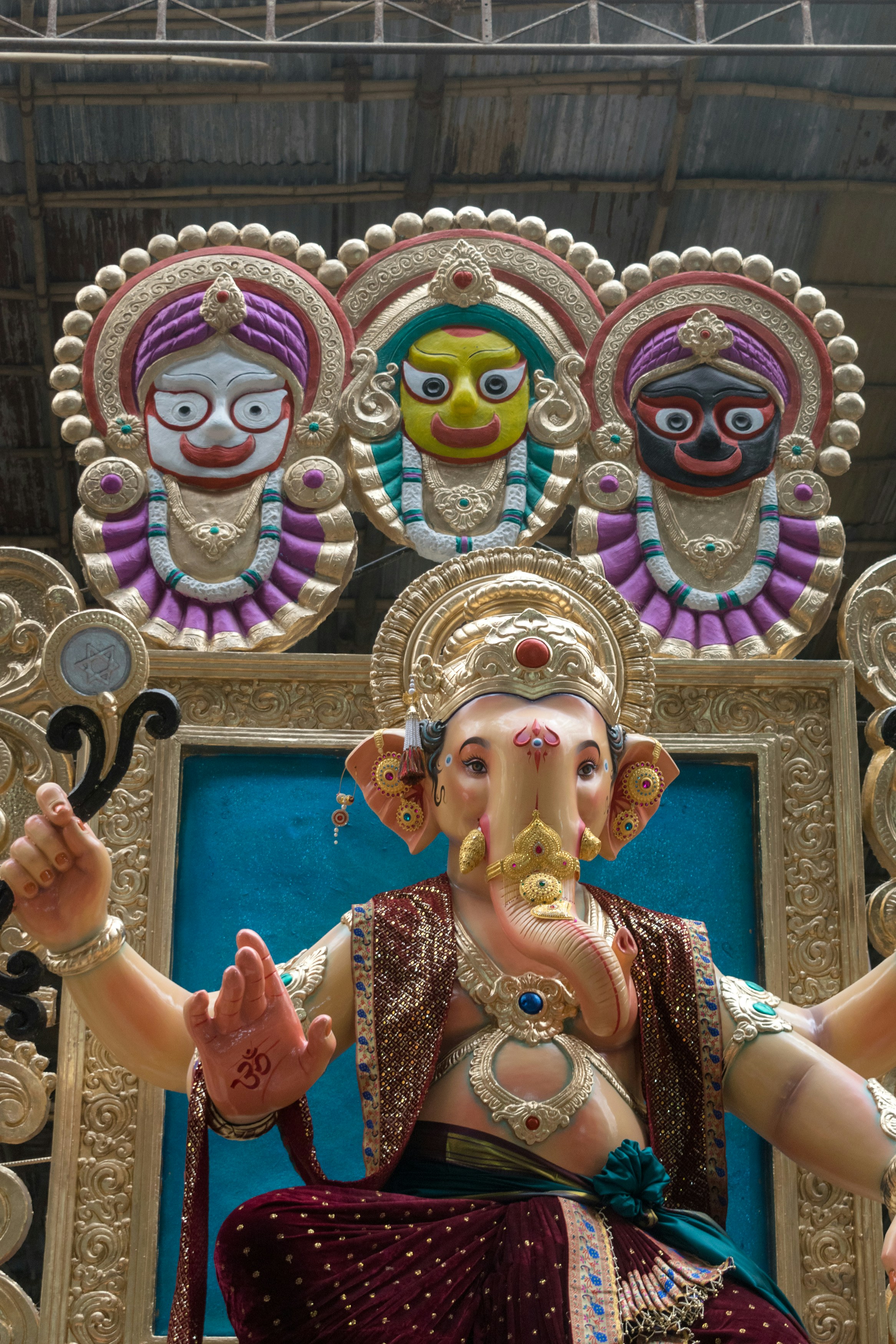 A Ganesha statue with three deities above in a procession in Mumbai, India