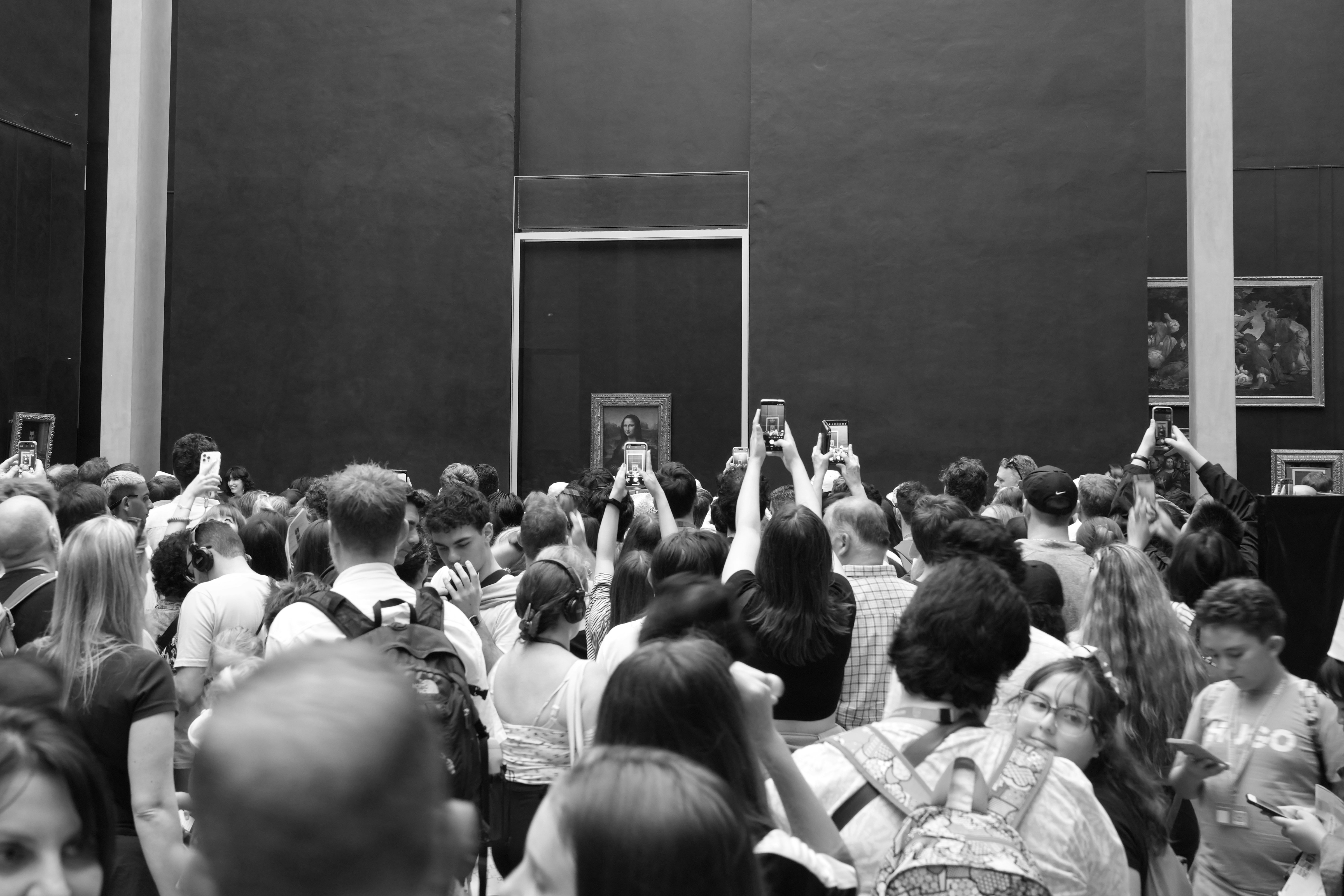 Una folla di persone che tengono in mano smartphone per fotografare la Mona Lisa a Parigi