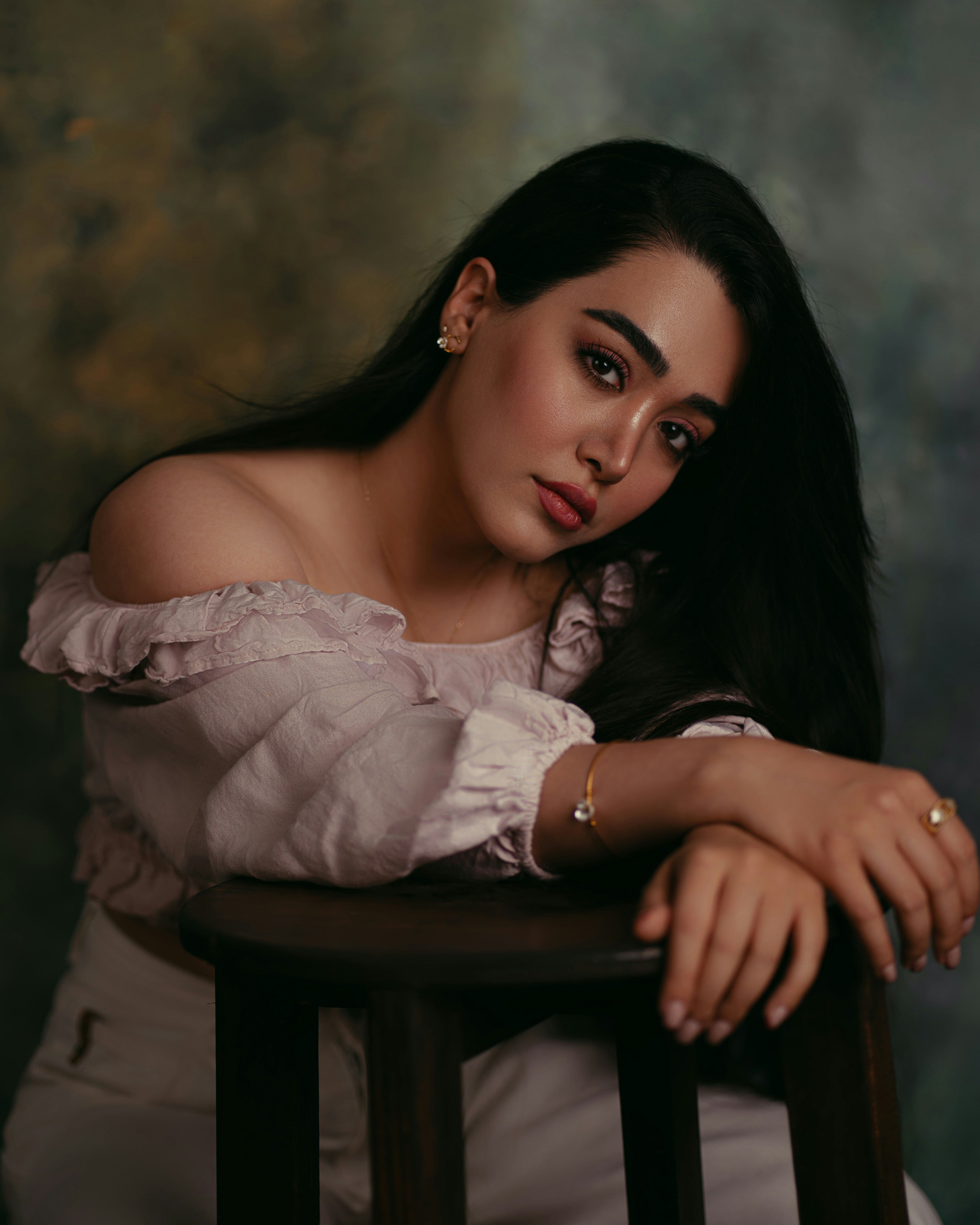 A woman with long dark hair wearing a pale pink off-the-shoulder top
