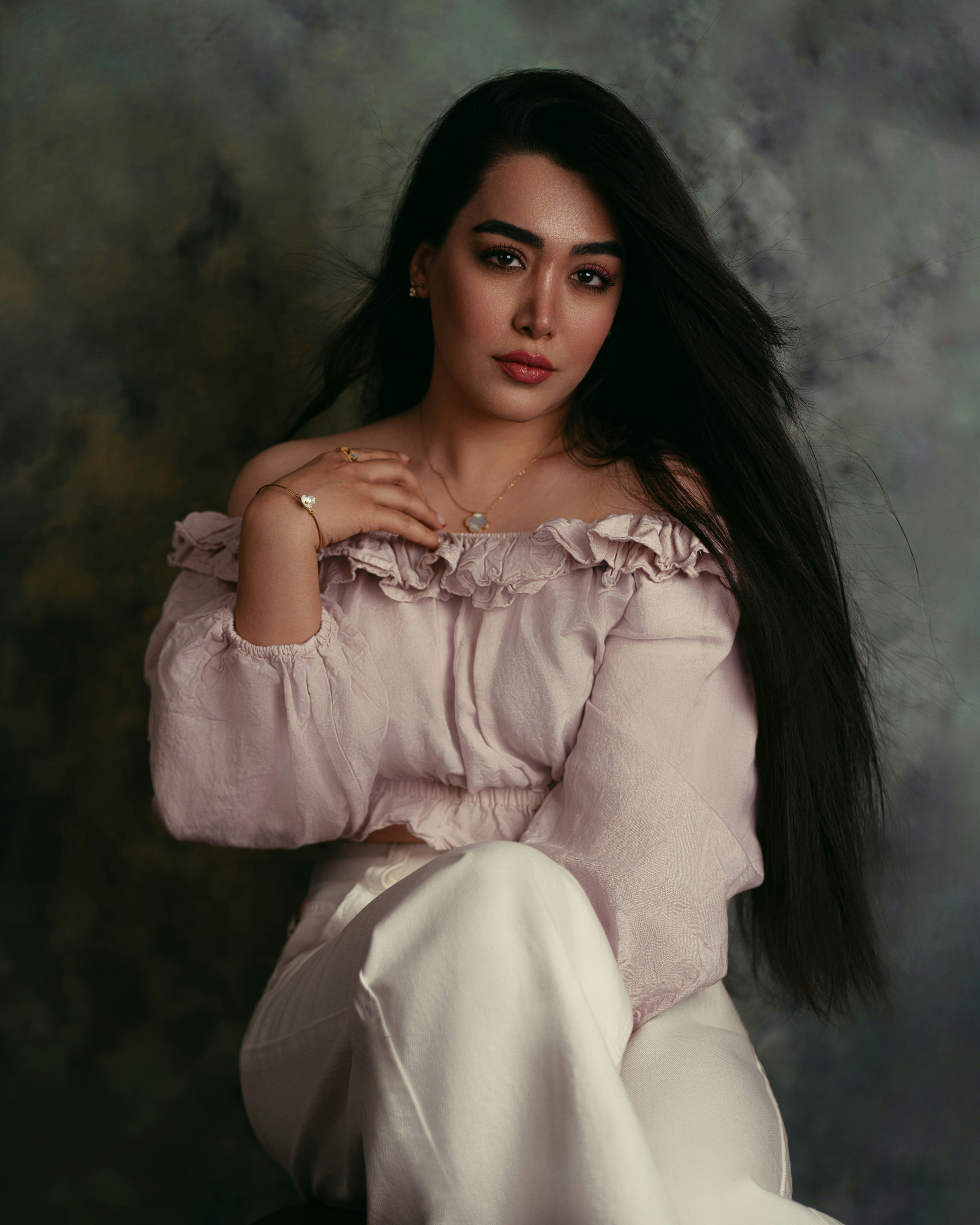 A woman with long dark hair wearing a pale pink off-shoulder top