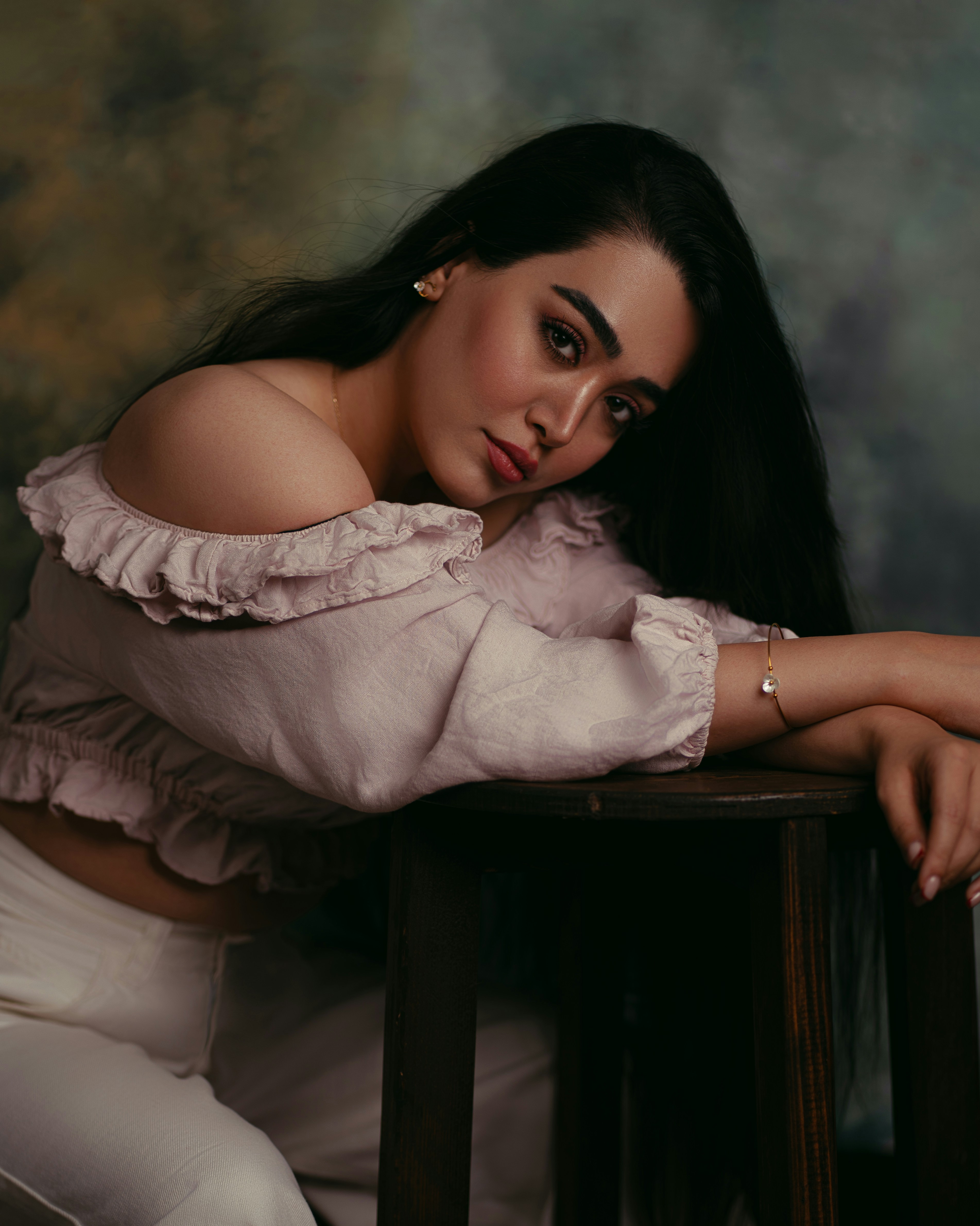 A woman with long dark hair wearing a ruffled pink off-shoulder top