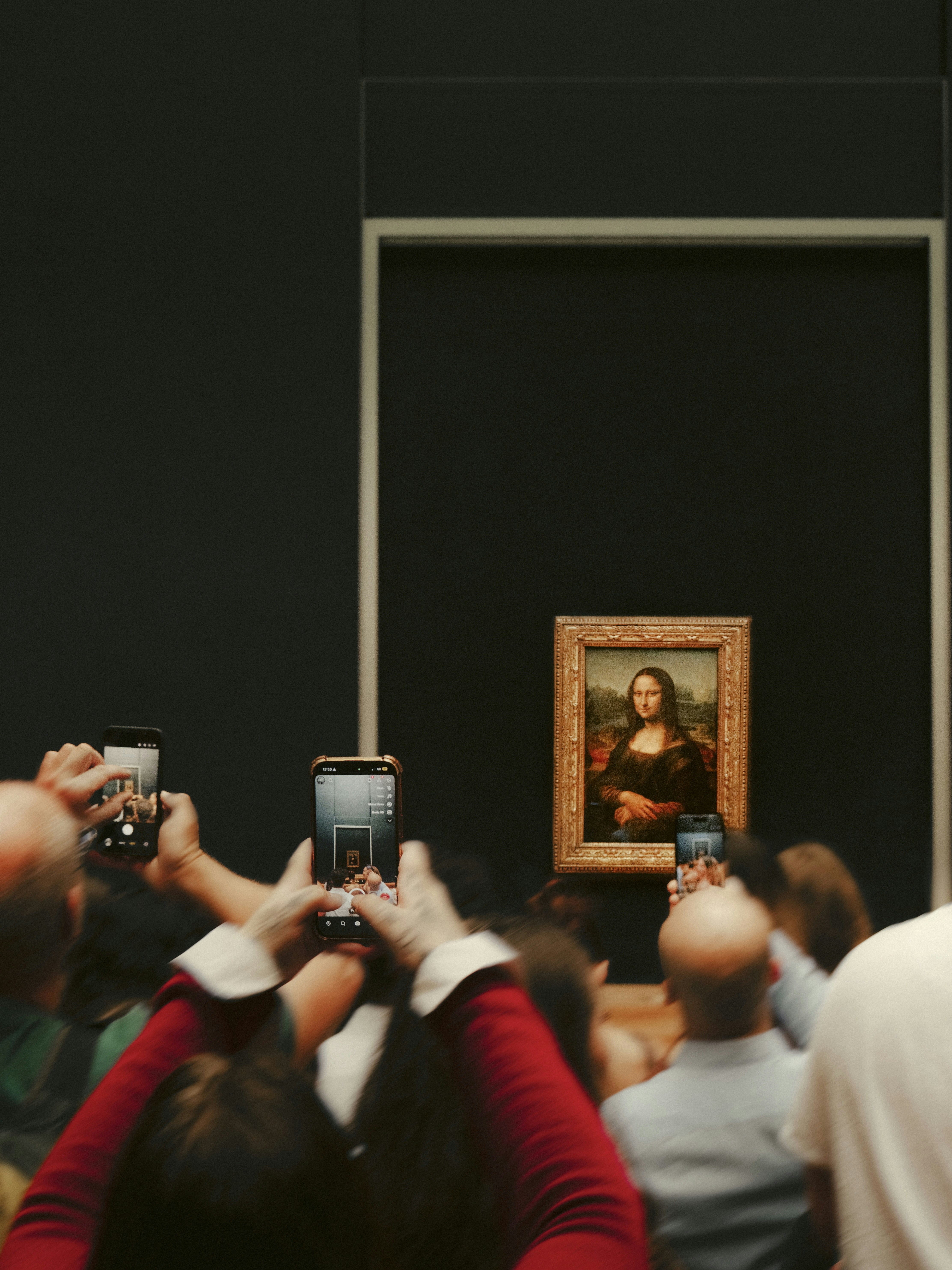 A crowd of people holding up smartphones to photograph the Mona Lisa in Paris