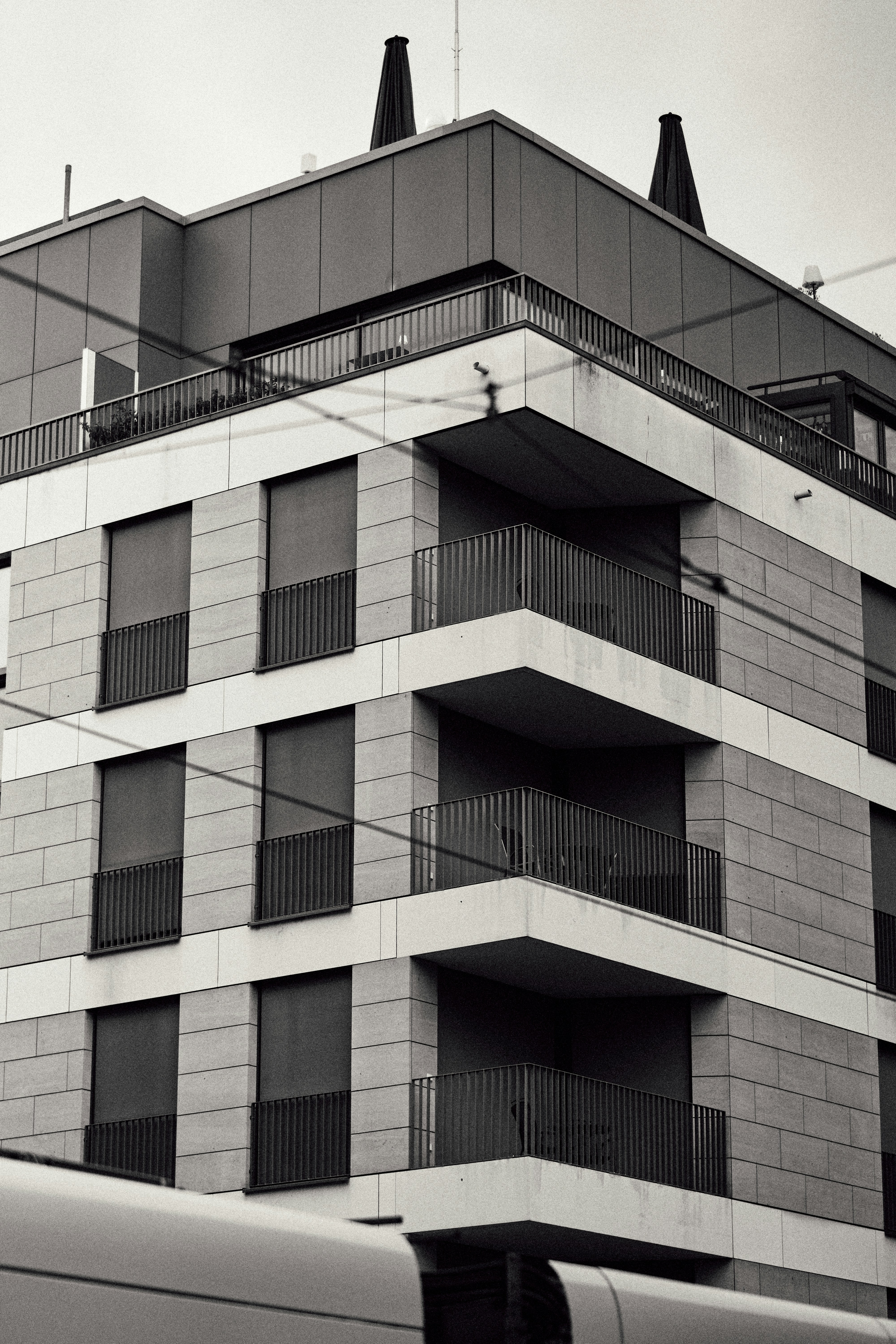 Un immeuble moderne avec façade en pierre, balcons et volets sombres