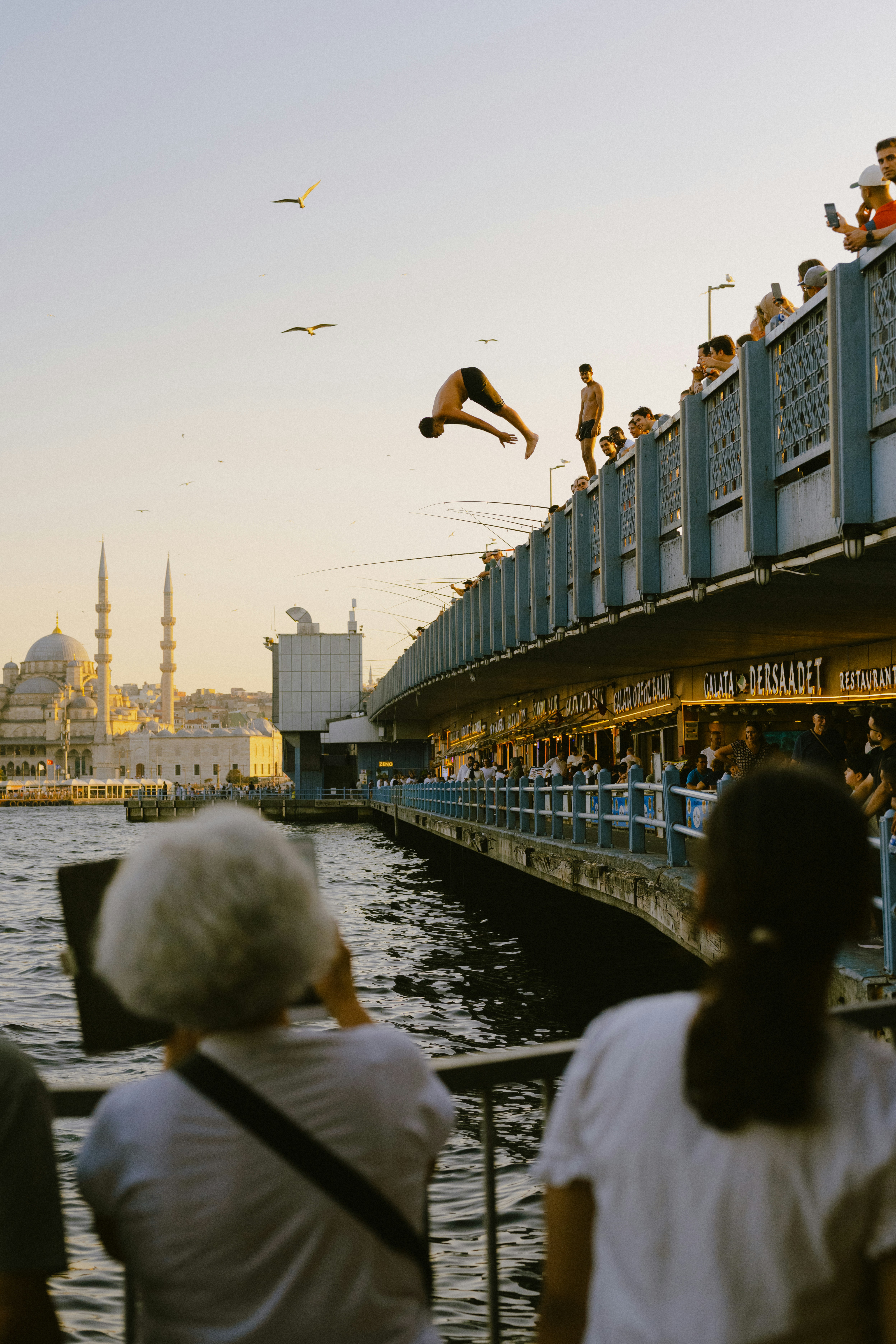A person diving from the Galata Bridge into the water in Istanbul