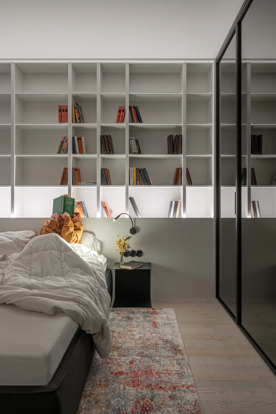 A person in an orange hoodie reading a book in a bed