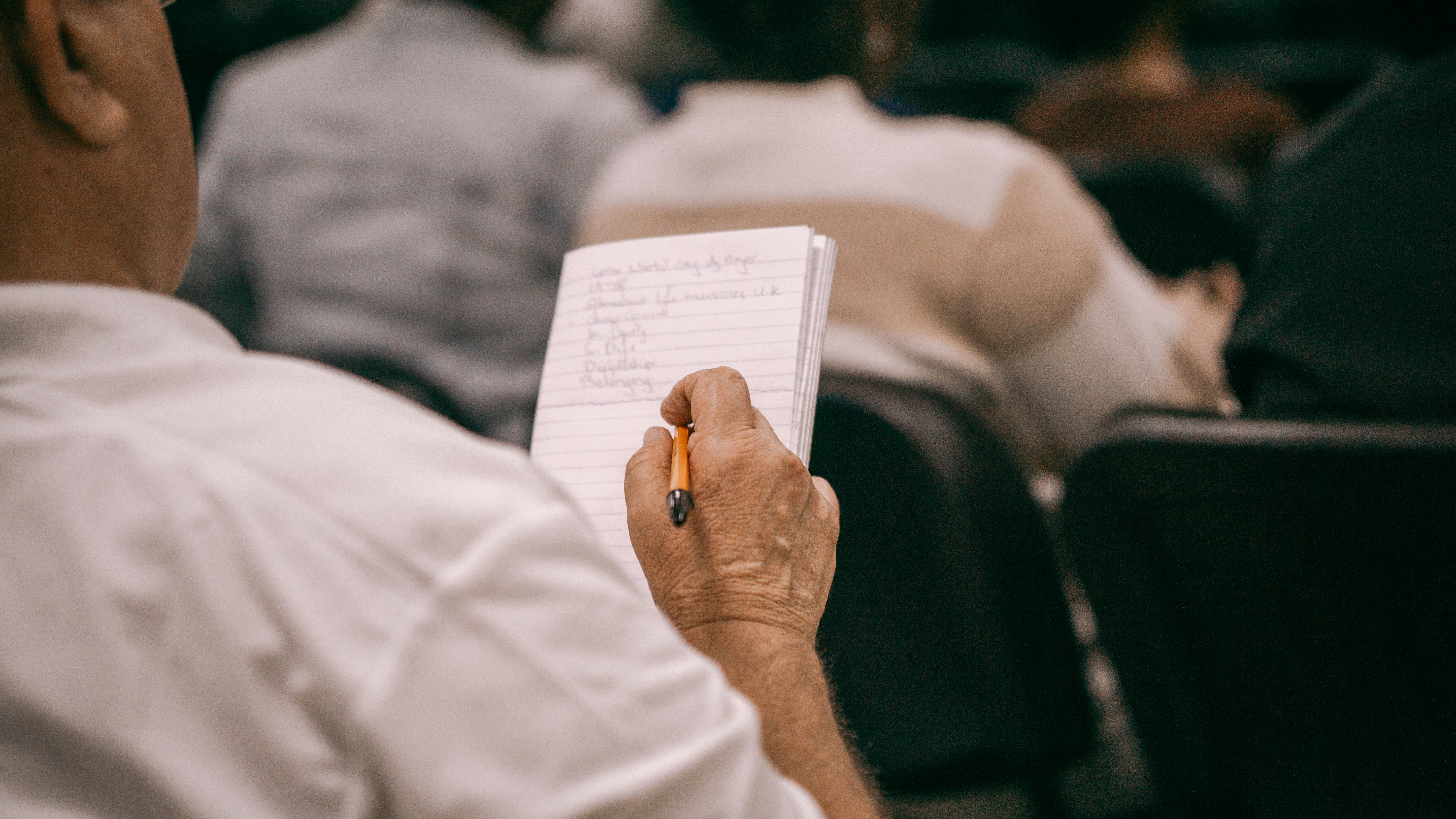 Persona tomando notas en un cuaderno durante una reunión